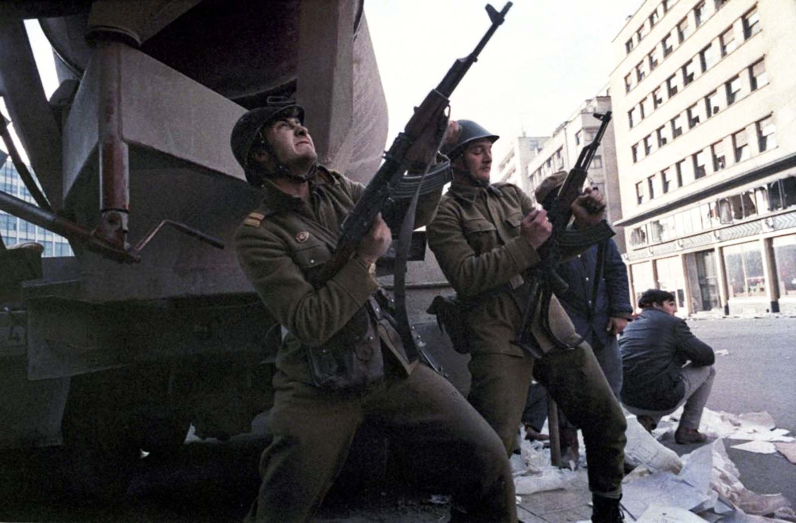 A Romanian soldier loads his automatic rifle as another shoots during heavy fighting against pro-Ceausescu troops in central Bucharest.