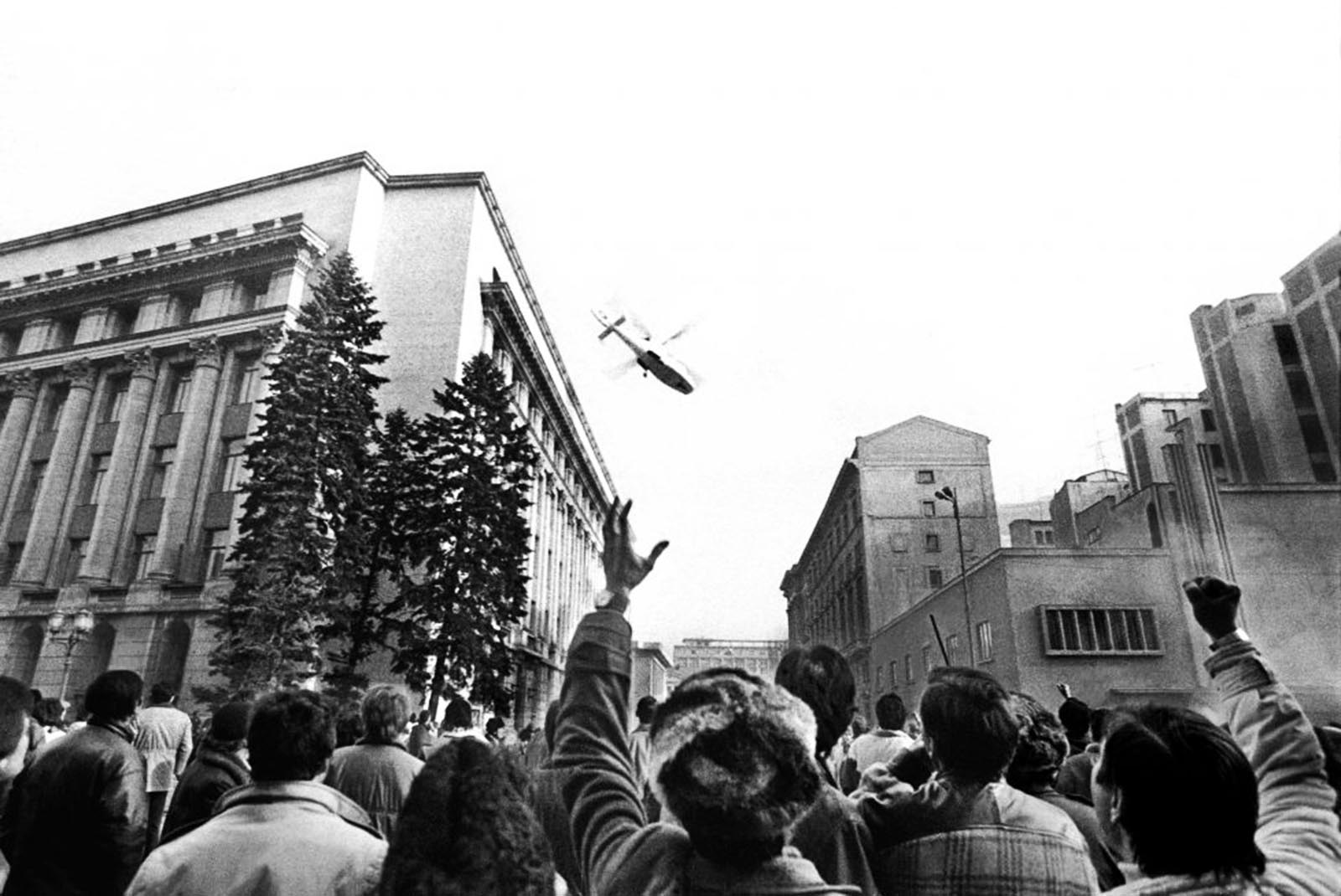 People gesturing towards a helicopter in which the country's communist dictator Nicolae Ceausescu fled the Romanian Communist Party Central Committee headquarters.