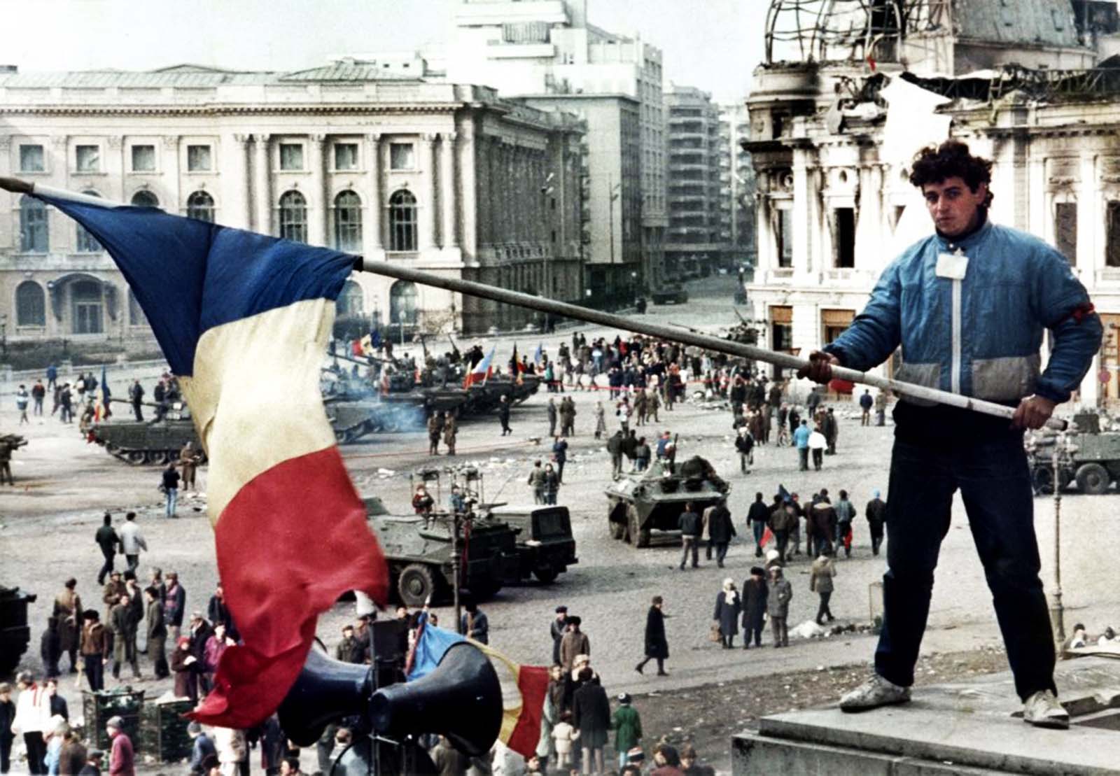 A young man waves a Romanian flag with the communist symbol cut out over Bucharest’s Republic Square on 26 December 1989, the day after Ceausescu was shot.
