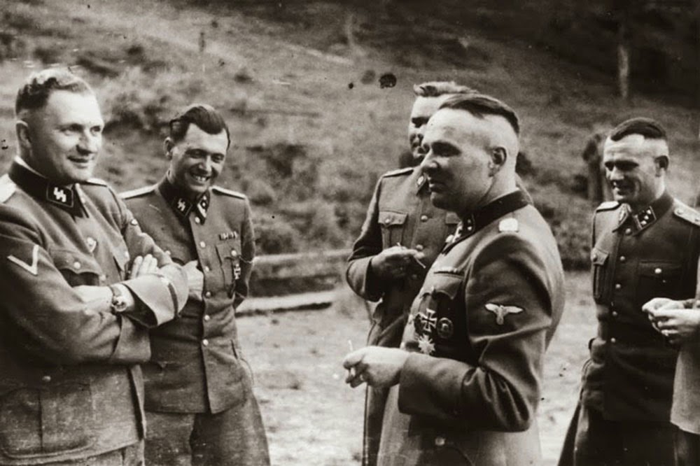 Taking a break. The second person is the notorious concentration camp doctor Josef Mengele (The Angel of the Death).