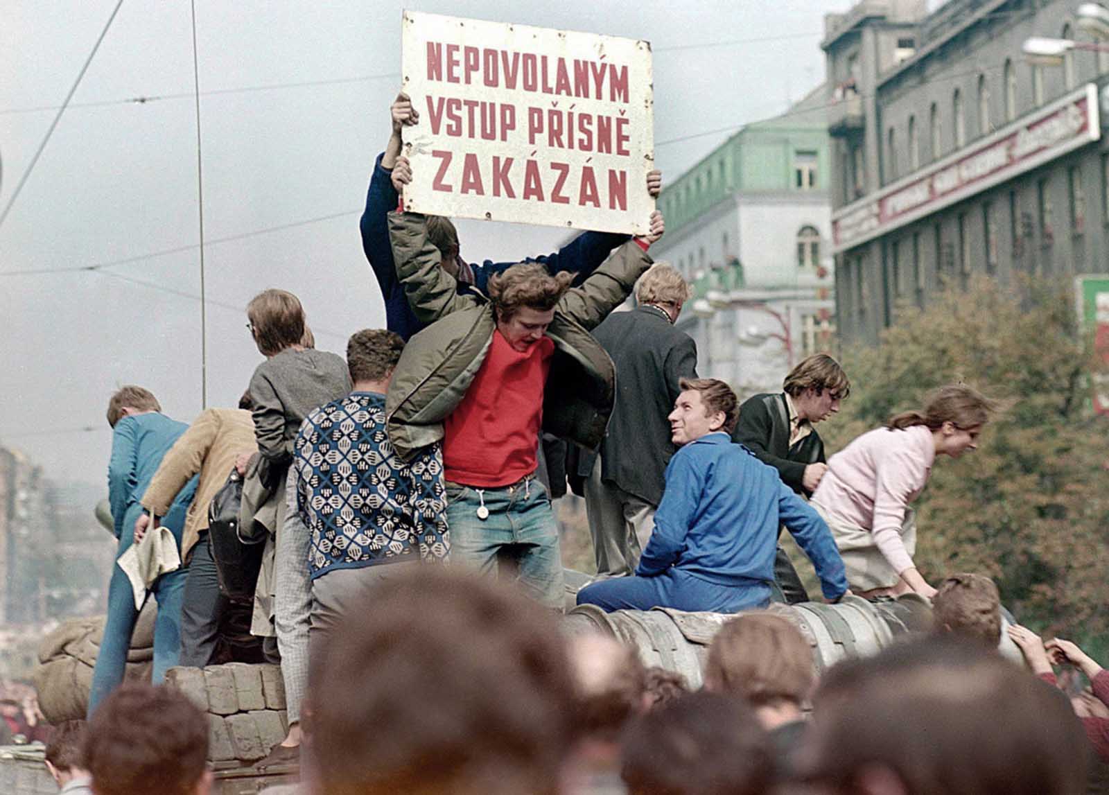 Prague residents ride on top of a Soviet army tank rolling down Wenceslas Square in central Prague during the first day of the Soviet-led invasion, on August 21, 1968. The banner reads: 