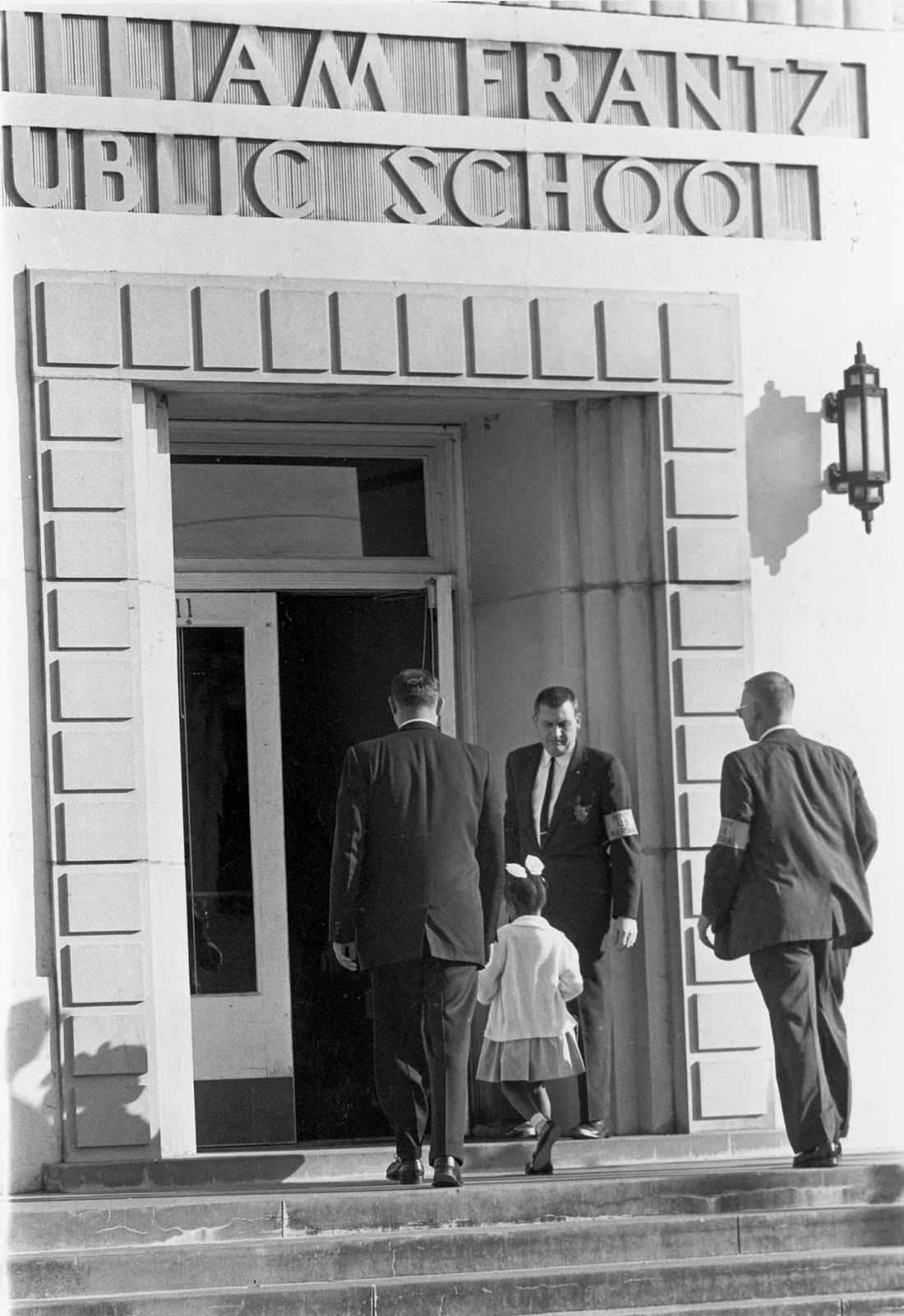 Guarded by three Deputy U.S. Marshals, including Charles Burks, top center, young Ruby Bridges enters newly integrated William Frantz school in New Orleans, La. on Dec. 5, 1960 to begin her third week as the only black student in the school.