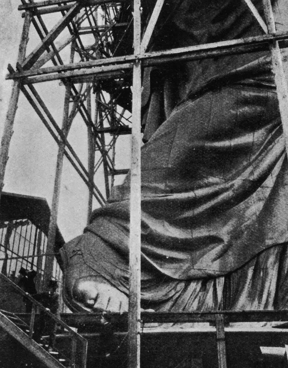 Tourists take a peek at Lady Liberty's massive foot as she is built in Paris before embarking on her long journey to the United States.