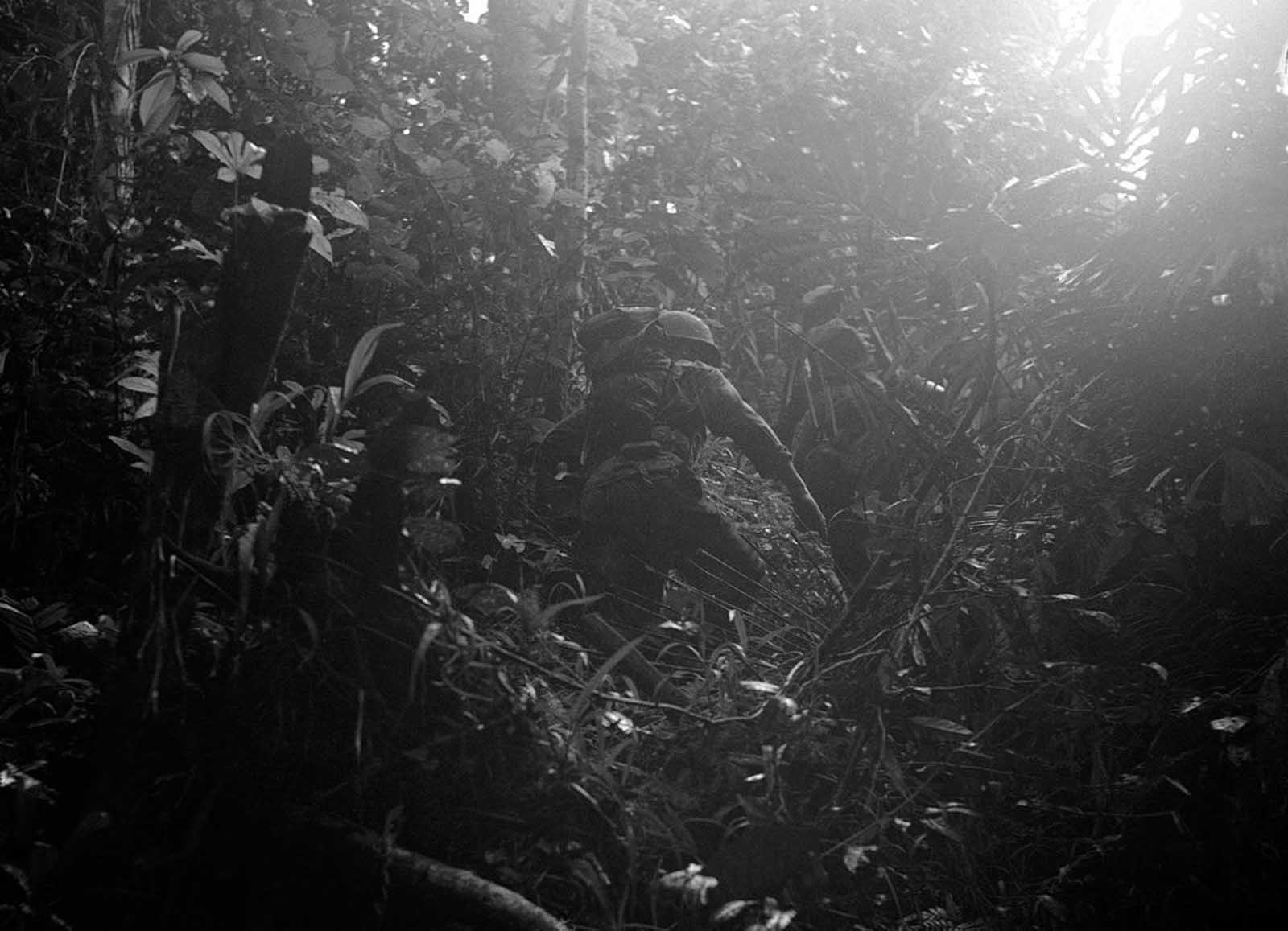 American reconnaissance patrol into the dense jungles of New Guinea, on December 18, 1942. Lt. Philip Winson had lost one of his boots while building a raft and he made a make-shift boot out of part of a ground sheet and straps from a pack.