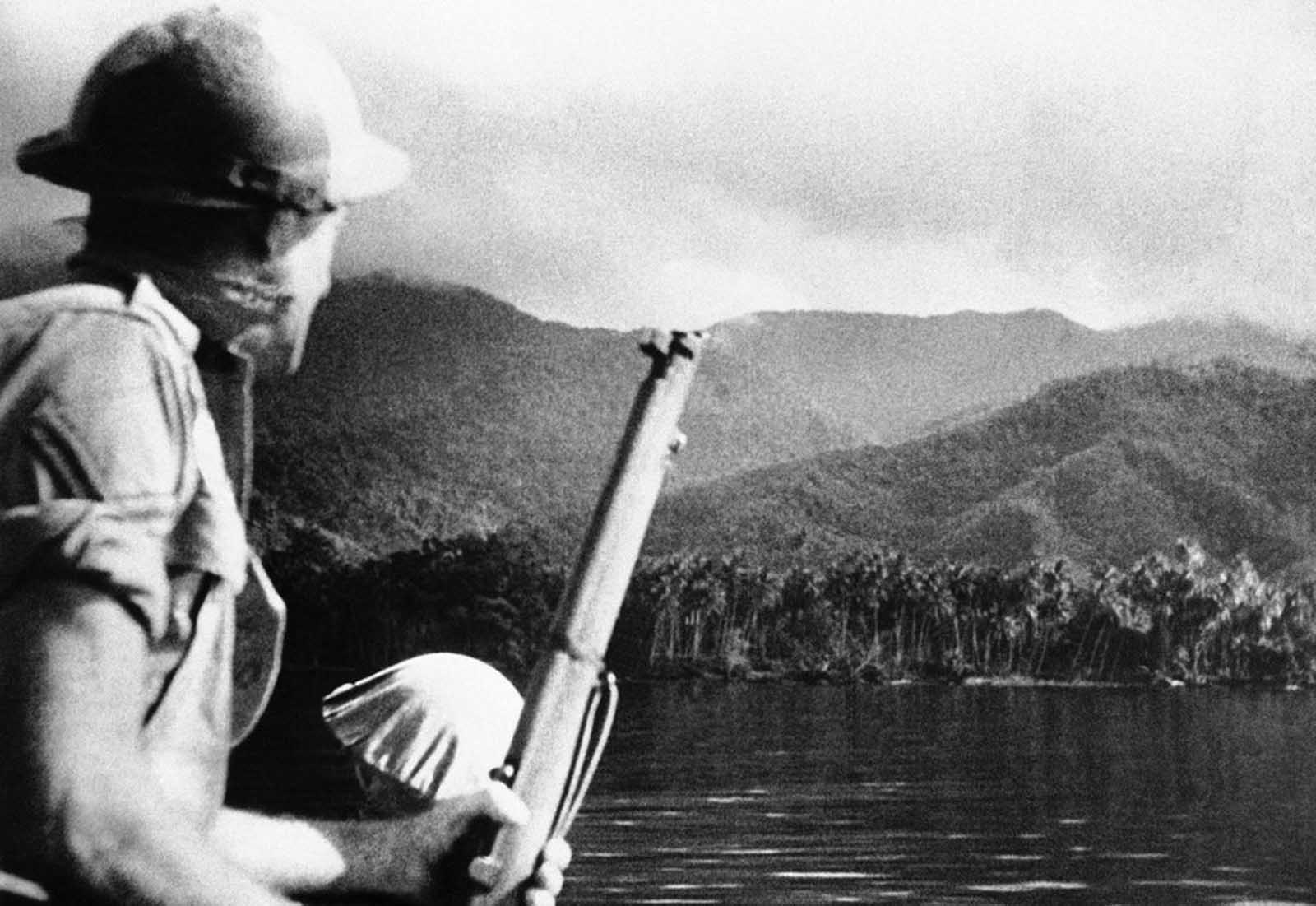 A helmeted Australian soldier, rifle in hand, looks out over a typical New Guinea landscape in the vicinity of Milne Bay on October 31, 1942, where an earlier Japanese attempt at invasion was defeated by the Australian defenders.
