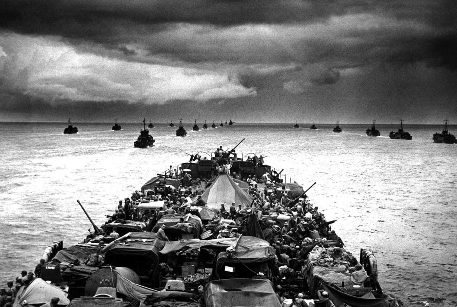 Columns of troop-packed LCIs (Landing Craft, Infantry) trail in the wake of a Coast Guard-manned LST (Landing Ship, Tank) en route to the invasion of Cape Sansapor, New Guinea in 1944.