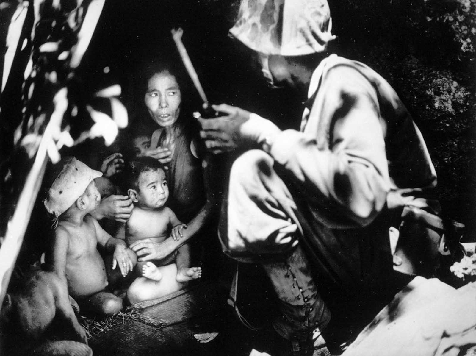 A member of a U.S. Marine patrol discovers this Japanese family hiding in a hillside cave, June 21, 1944, on Saipan. The mother, four children and a dog took shelter in the cave from the fierce fighting in the area during the U.S. invasion of the Mariana Islands.