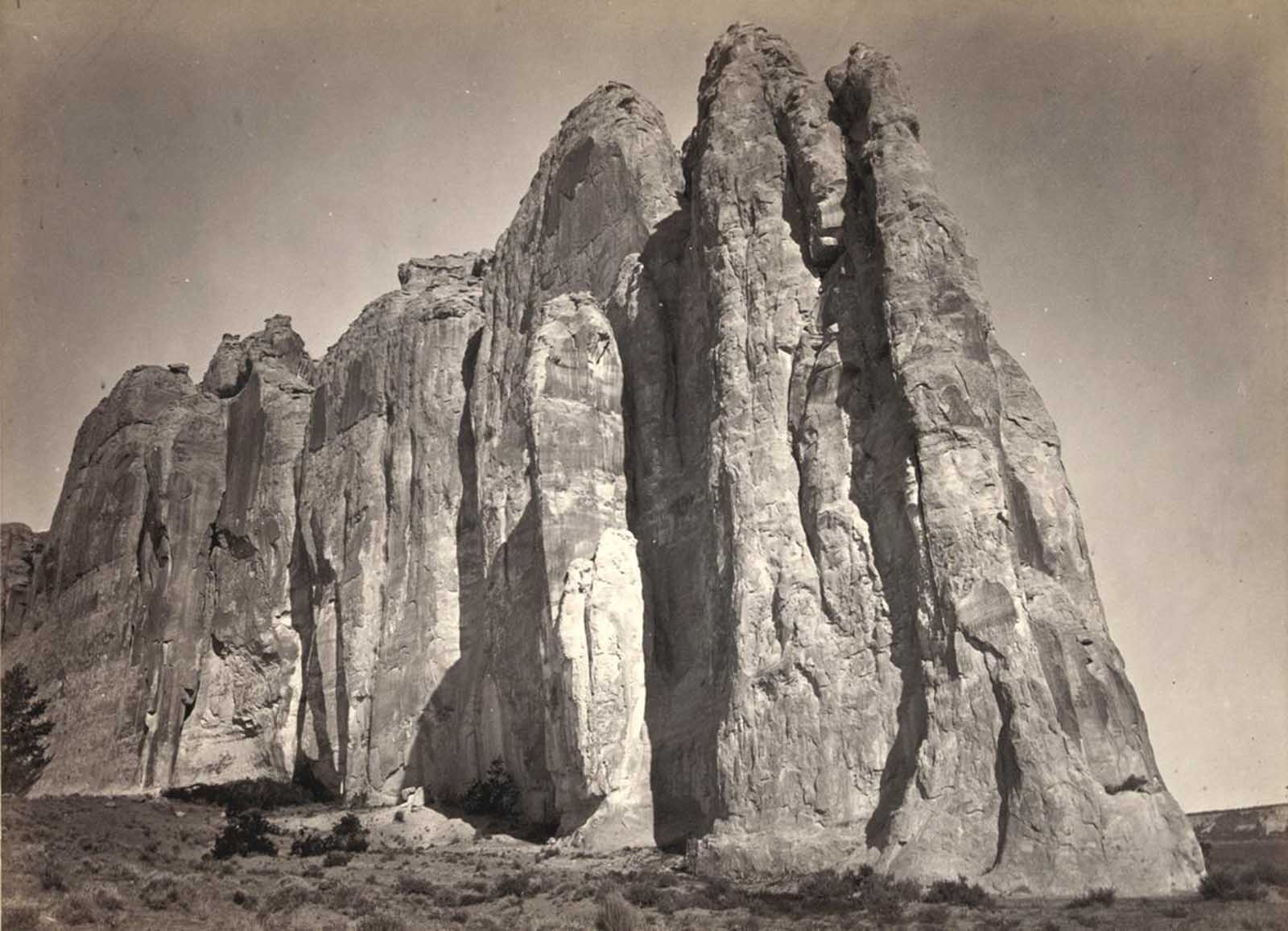 The south side of Inscription Rock (now El Morro National Monument), in New Mexico in 1873. Note the small figure of a man standing at bottom center. The prominent feature stands near a small pool of water, and has been a resting place for travelers for centuries. Since at least the 17th century, natives, Europeans, and later American pioneers carved names and messages into the rock face as they paused. In 1906, a law was passed, prohibiting further carving.