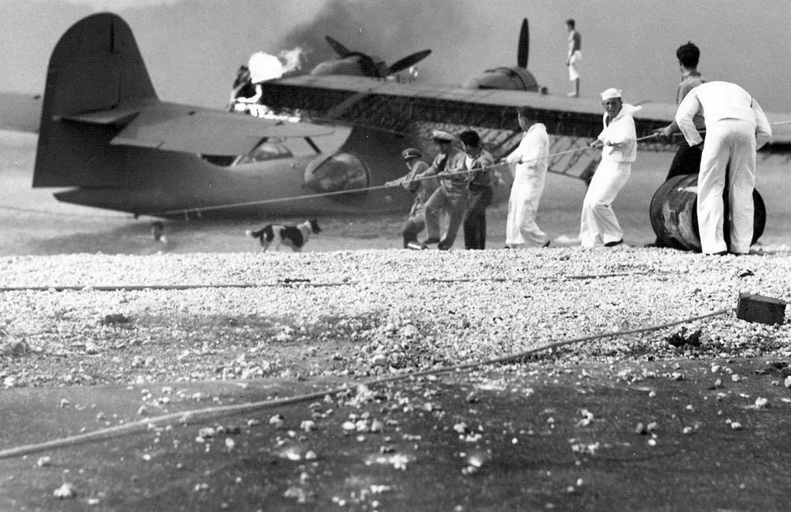 Sailors at Naval Air Station (NAS) Kaneohe attempt to salvage a burning PBY Catalina in the aftermath of the Japanese attack on Pearl Harbor.