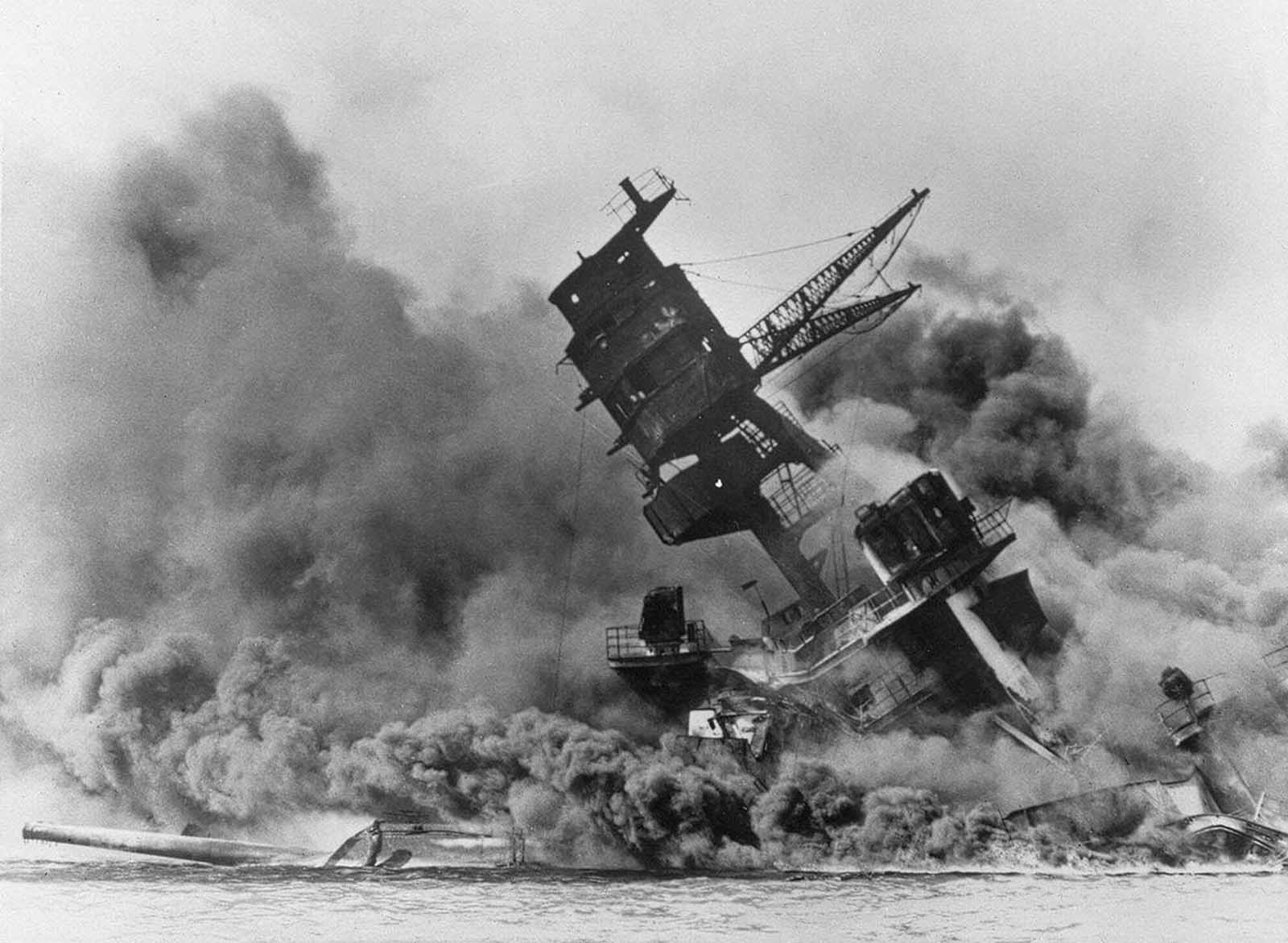The battleship USS Arizona belches smoke as it topples over into the sea during a Japanese surprise attack on Pearl Harbor, Hawaii.