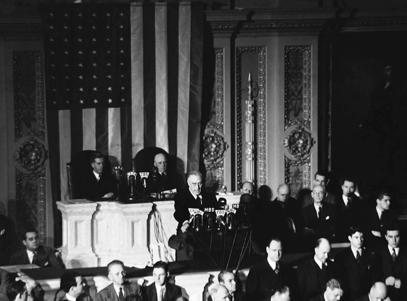 Declaring Japan guilty of a dastardly unprovoked attack, U.S. President Franklin D. Roosevelt asked Congress to declare war, on December 8, 1941. Listening are Vice President Henry Wallace, left, and House Speaker Sam Rayburn.