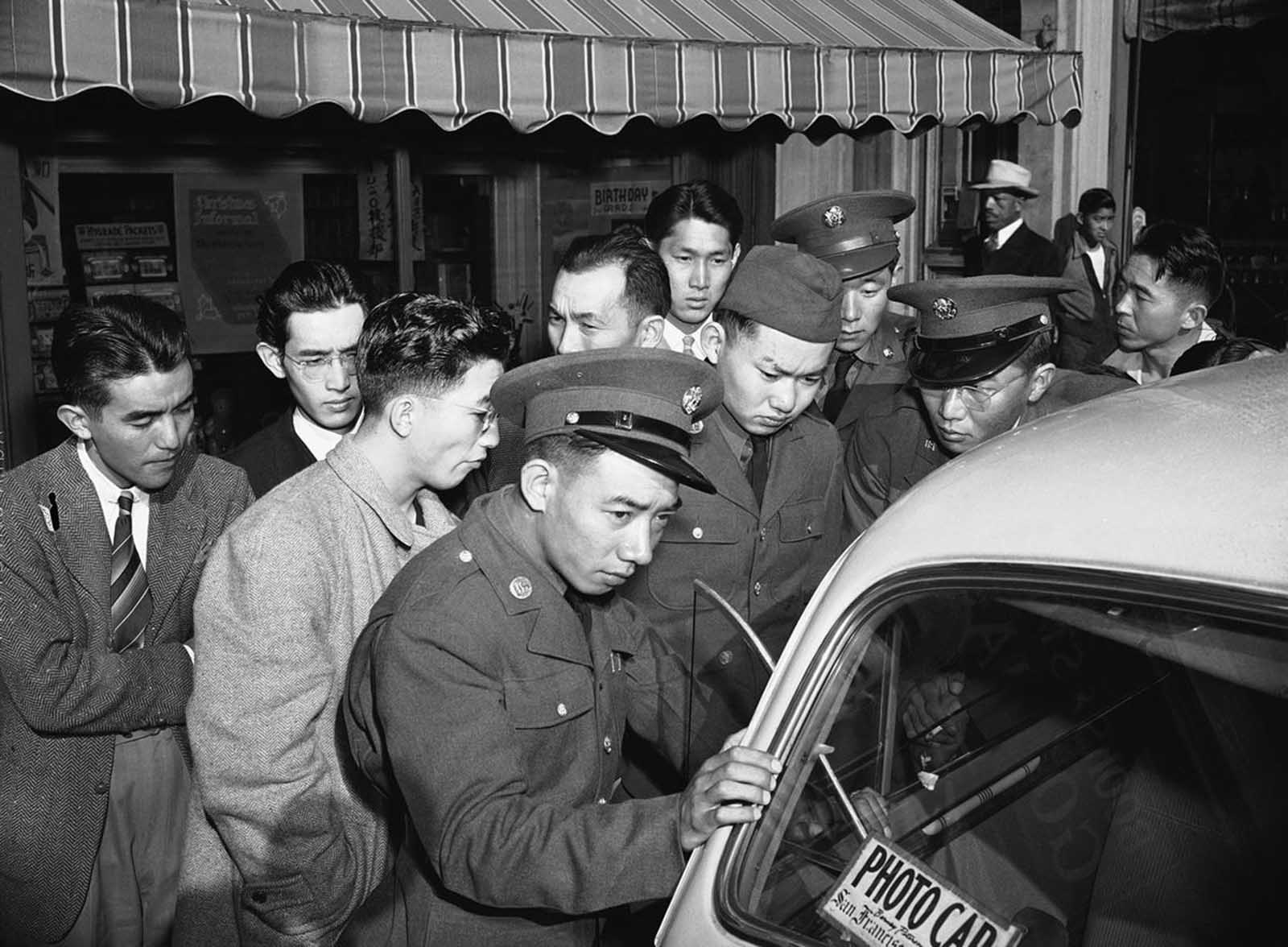 Young Japanese Americans, including several Army selectees, gather around a reporter's car in the Japanese section of San Francisco, on December 8, 1941