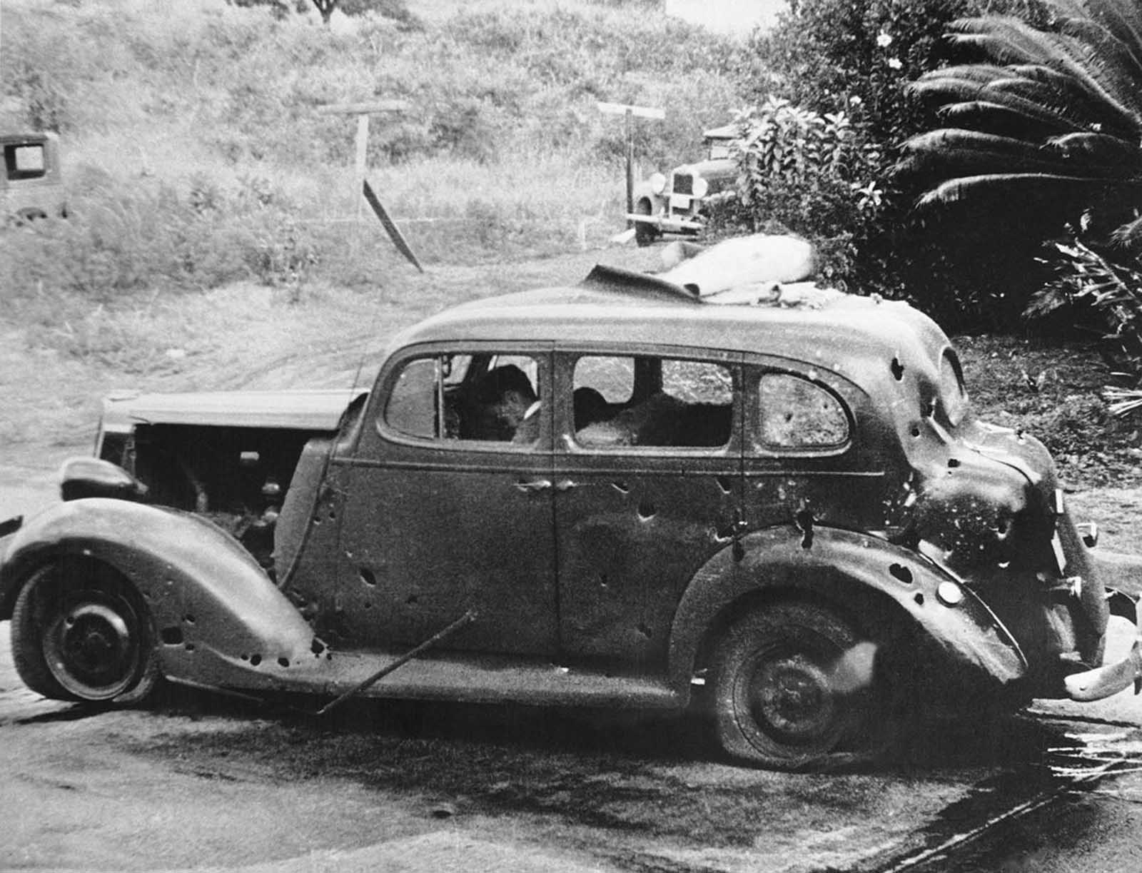In this photo provided by the U.S. Navy, eight miles from Pearl Harbor, shrapnel from a Japanese bomb riddled this car and killed three civilians in the attack of December 7, 1941. Two of the victims can be seen in the front seat. The Navy reported there was no nearby military target.