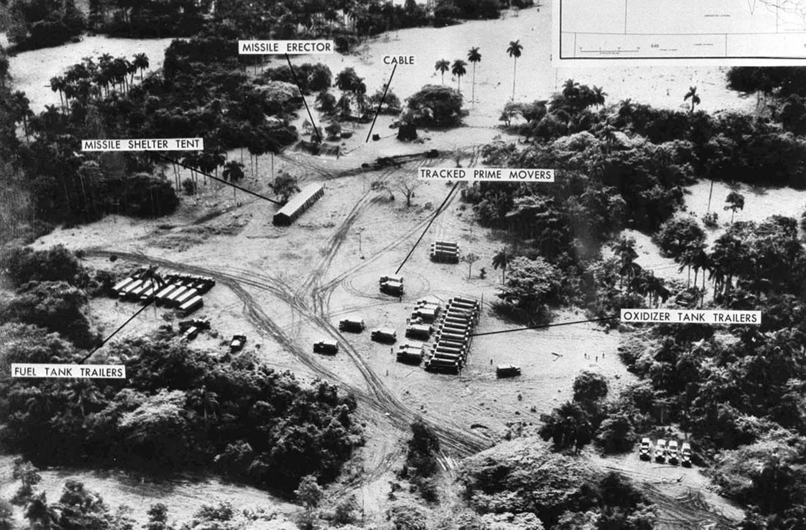 Evidence presented by the U.S. Department of Defense, of Soviet missiles in Cuba. This low level photo, made October 23, 1962, of the medium range ballistic missile site under construction at Cuba's San Cristobal area. A line of oxidizer trailers is at center. Added since October 14, the site was earlier photographed, are fuel trailers, a missile shelter tent, and equipment. The missile erector now lies under canvas cover. Evident also are extensive vehicle tracks and the construction of cable lines to control areas.