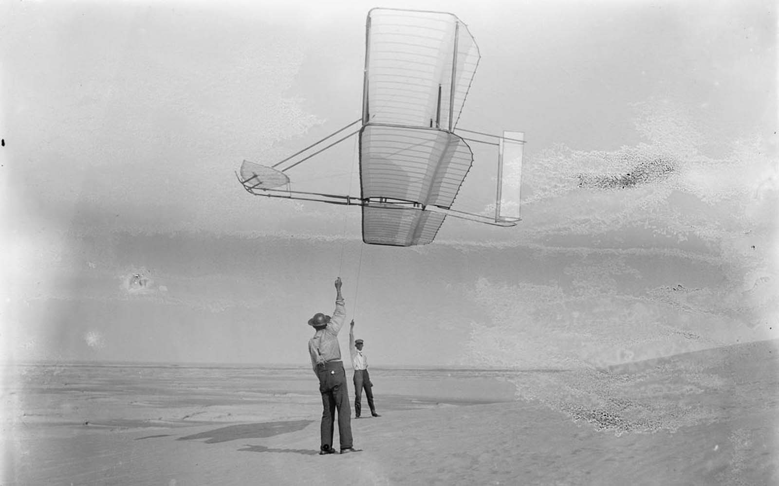 Side view of Dan Tate, left, and Wilbur Wright, right, flying the 1902 glider as a kite, on September 19, 1902.
