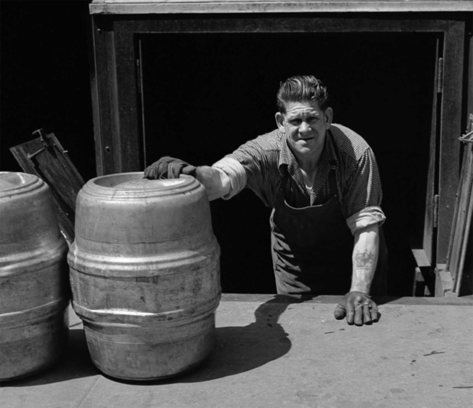 A man loads kegs of beer into a bar basement in 1953.