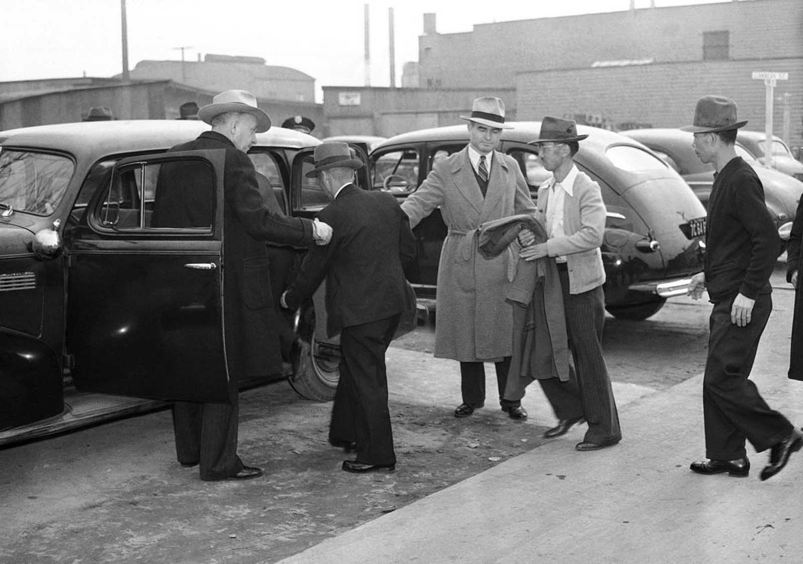Two plainclothes men, left, watch as Japanese aliens are removed from their homes on Terminal Island, a vital Naval and Shipbuilding center in Los Angeles, California, on February 3, 1942. Some 400 male Japanese aliens -- Terminal Island residents -- were rounded up early on February 2 by 180 federal, city and county officers.