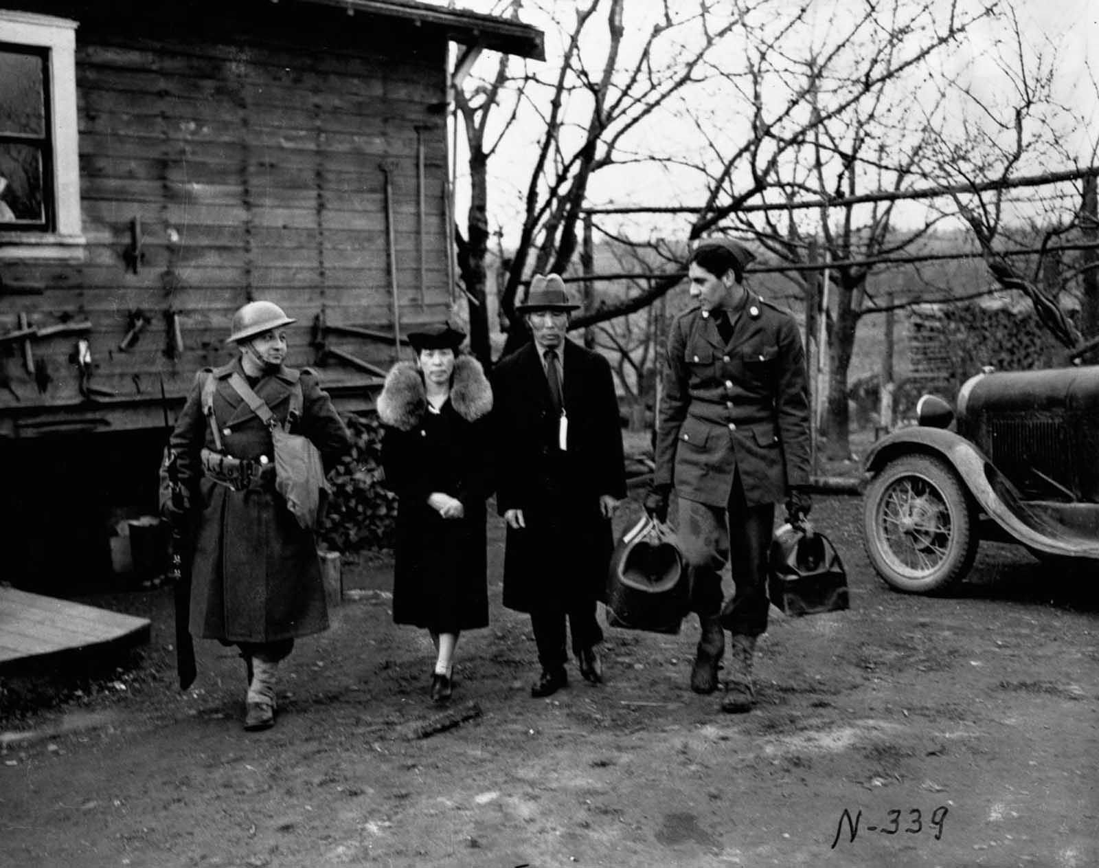 Soldiers escort an elderly Japanese-American couple from their home on Bainbridge Island, Washington.