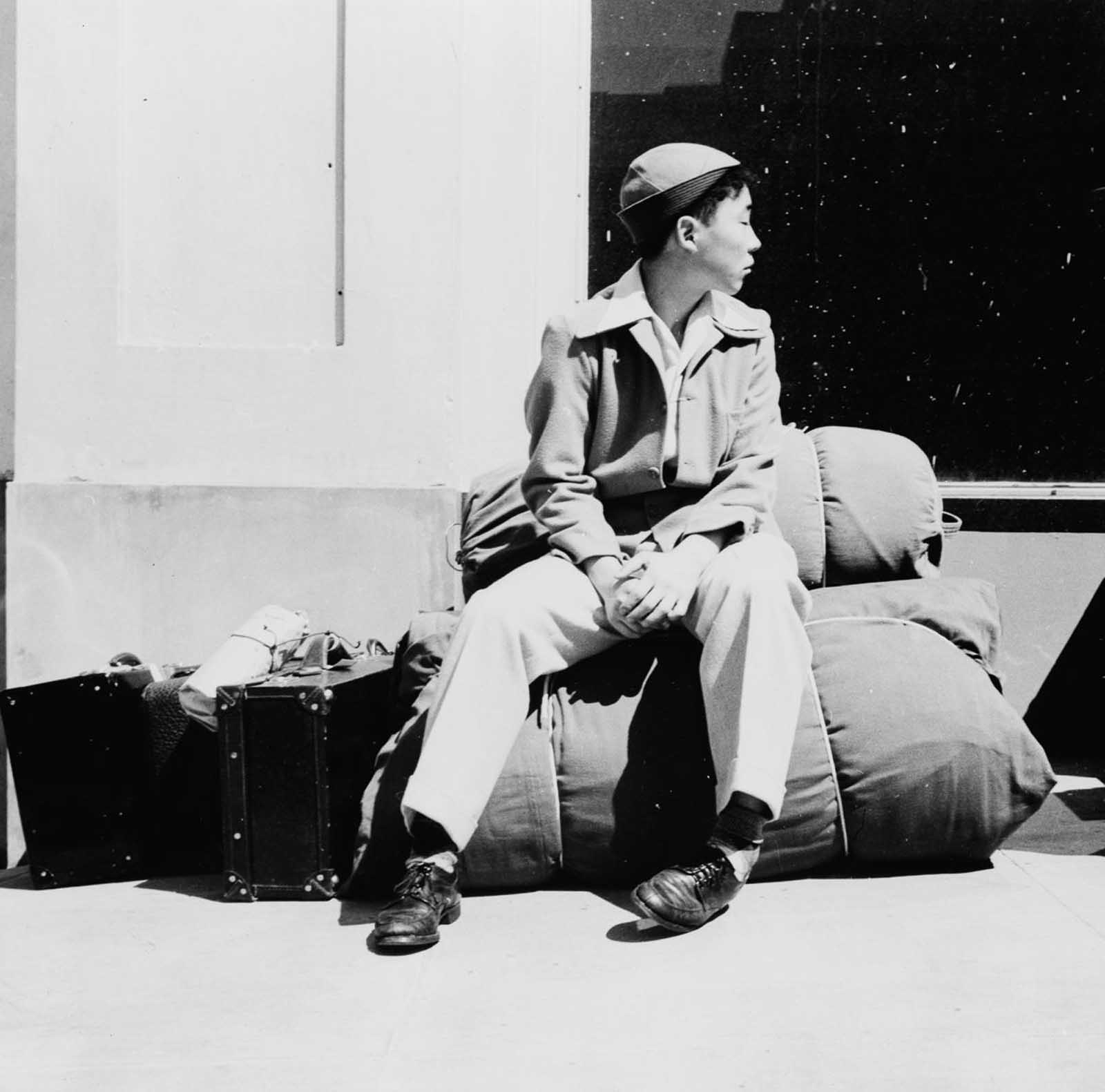 A boy sits on his belongings as he awaits relocation from San Francisco.