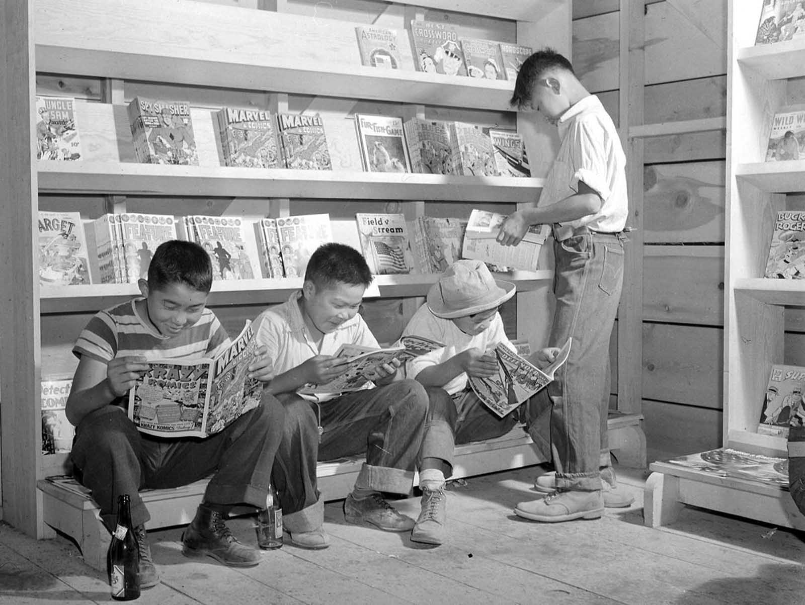 Four young evacuees from Sacramento, California, read comic books at the newsstand in the Tule Lake Relocation Center, in Newell, California, on July 1, 1942.