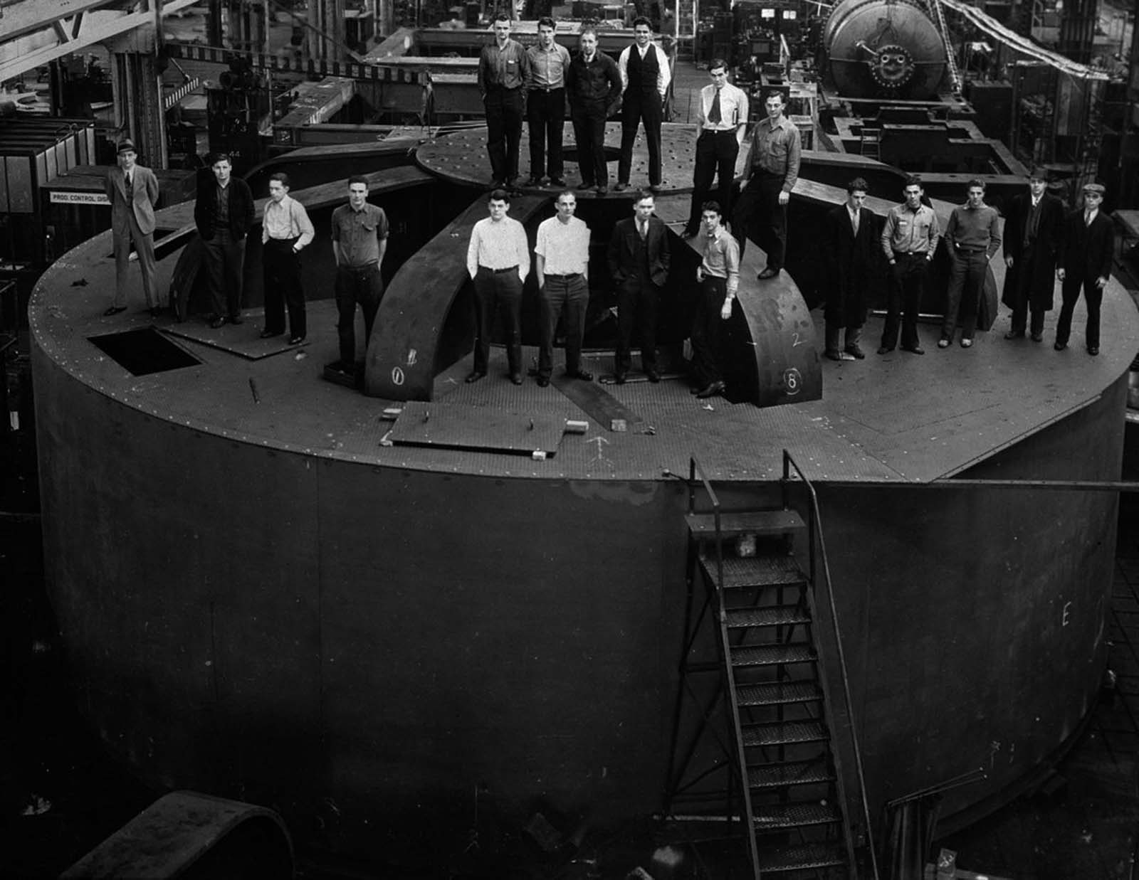 Student engineers stand atop one of the 2 million-pound hydroelectric generators for the dam at the General Electric factory in Schenectady, New York. 1935.