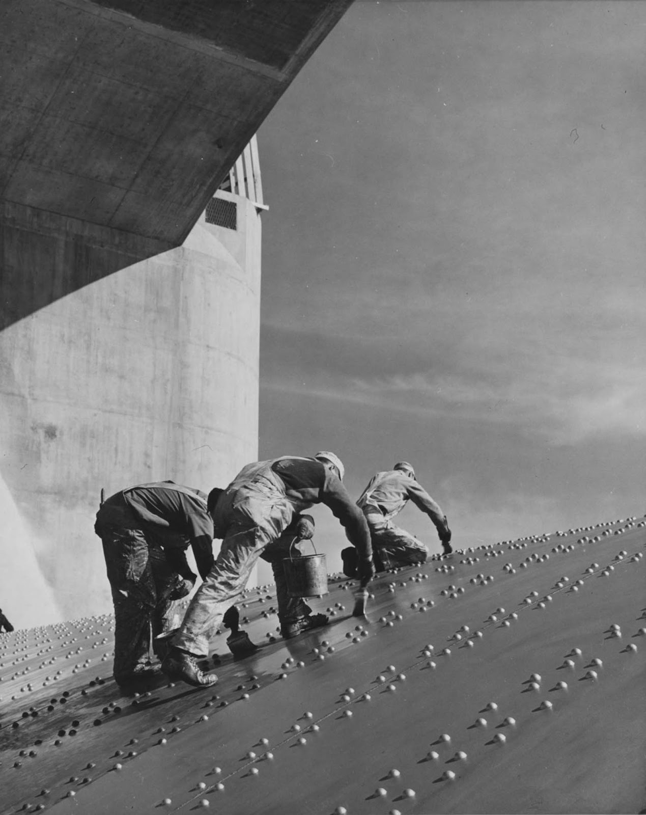 Workers apply a coat of paint to one of the dam's spillways. 1936.