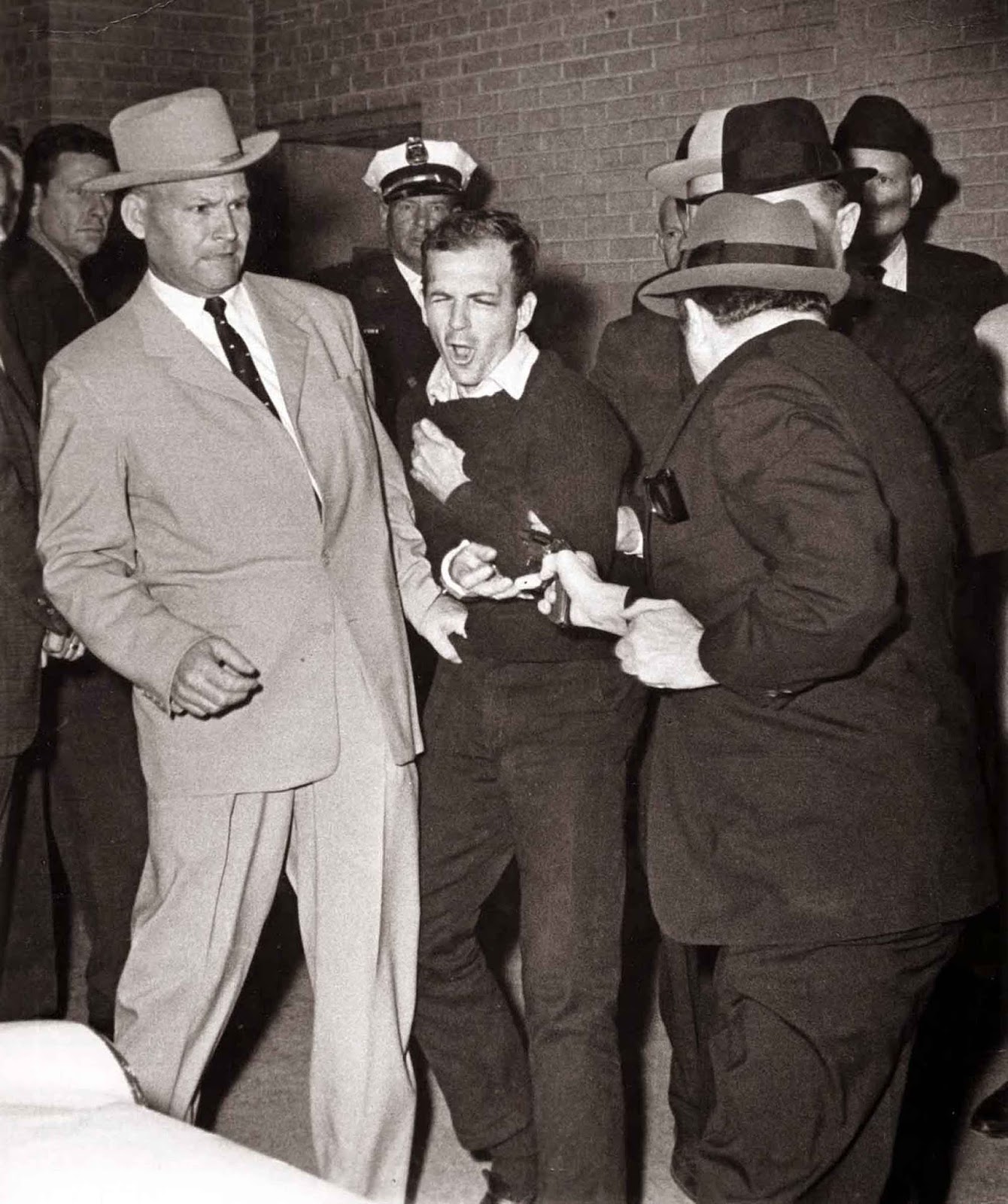 Ruby about to shoot Oswald who is being escorted by Dallas police. Det. Jim Leavelle is wearing the tan suit. Det. L.C. Graves is wearing the dark suit.
