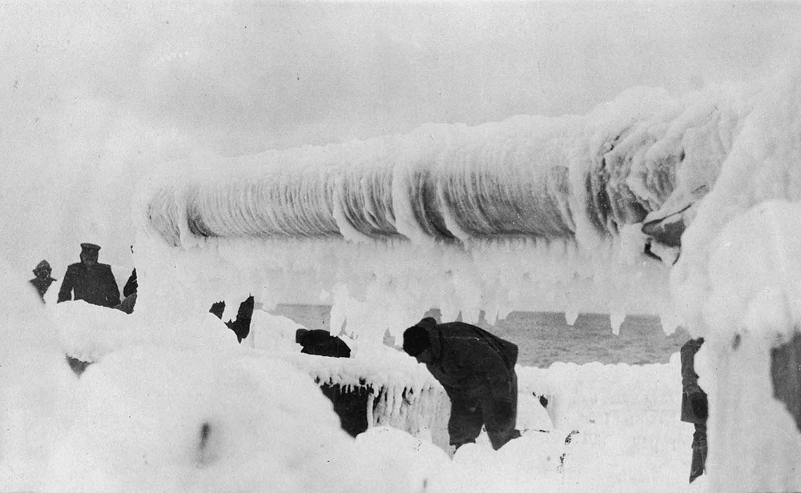 Men on deck of a ship removing ice. Original caption: 