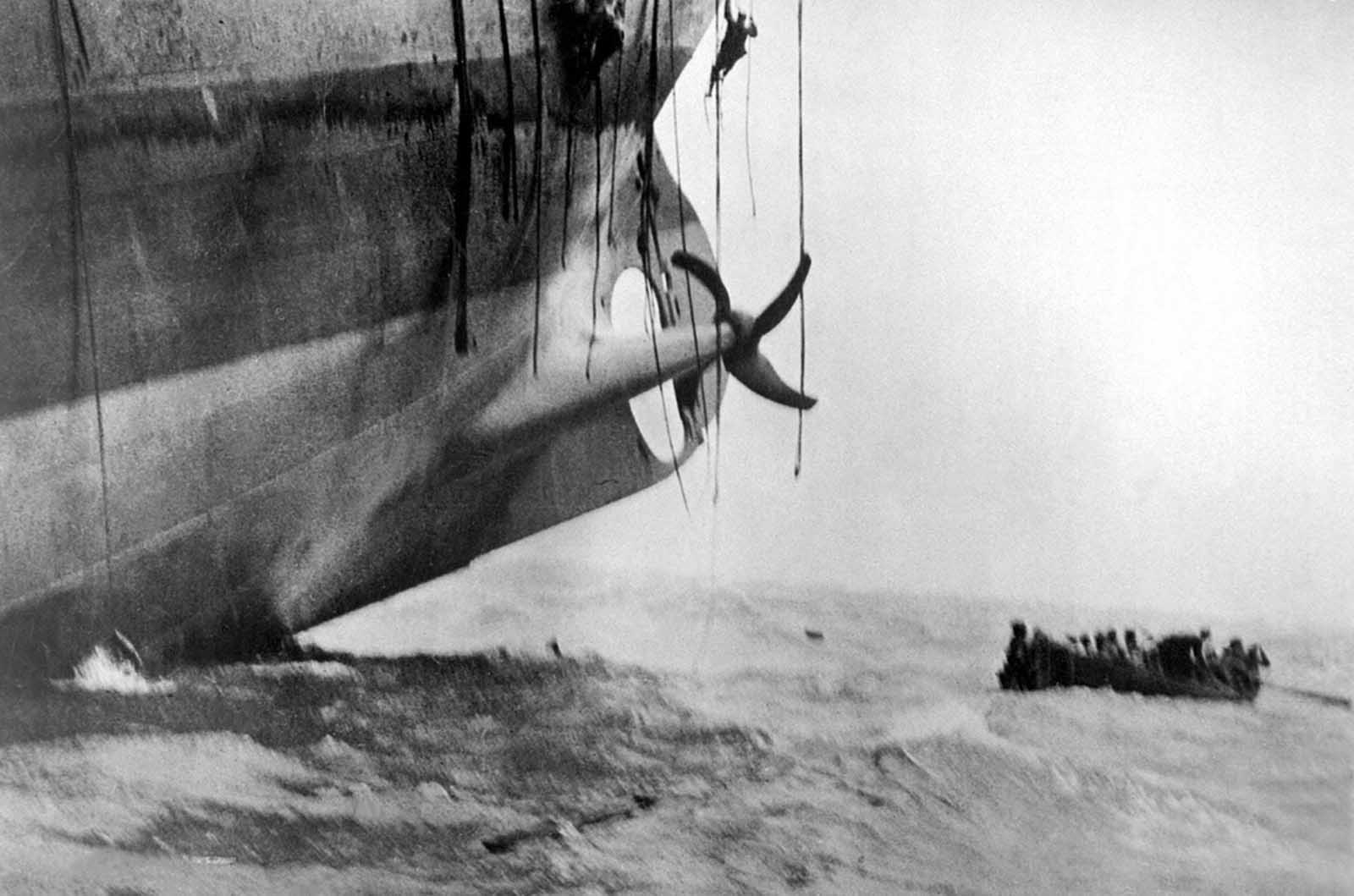 Last minute escape from a vessel torpedoed by a German sub. The vessel has already sunk its bow into the waves, and her stern is slowly lifting out of the water. Men can be seen sliding down ropes as the last boat is pulling away. Ca. 1917. 