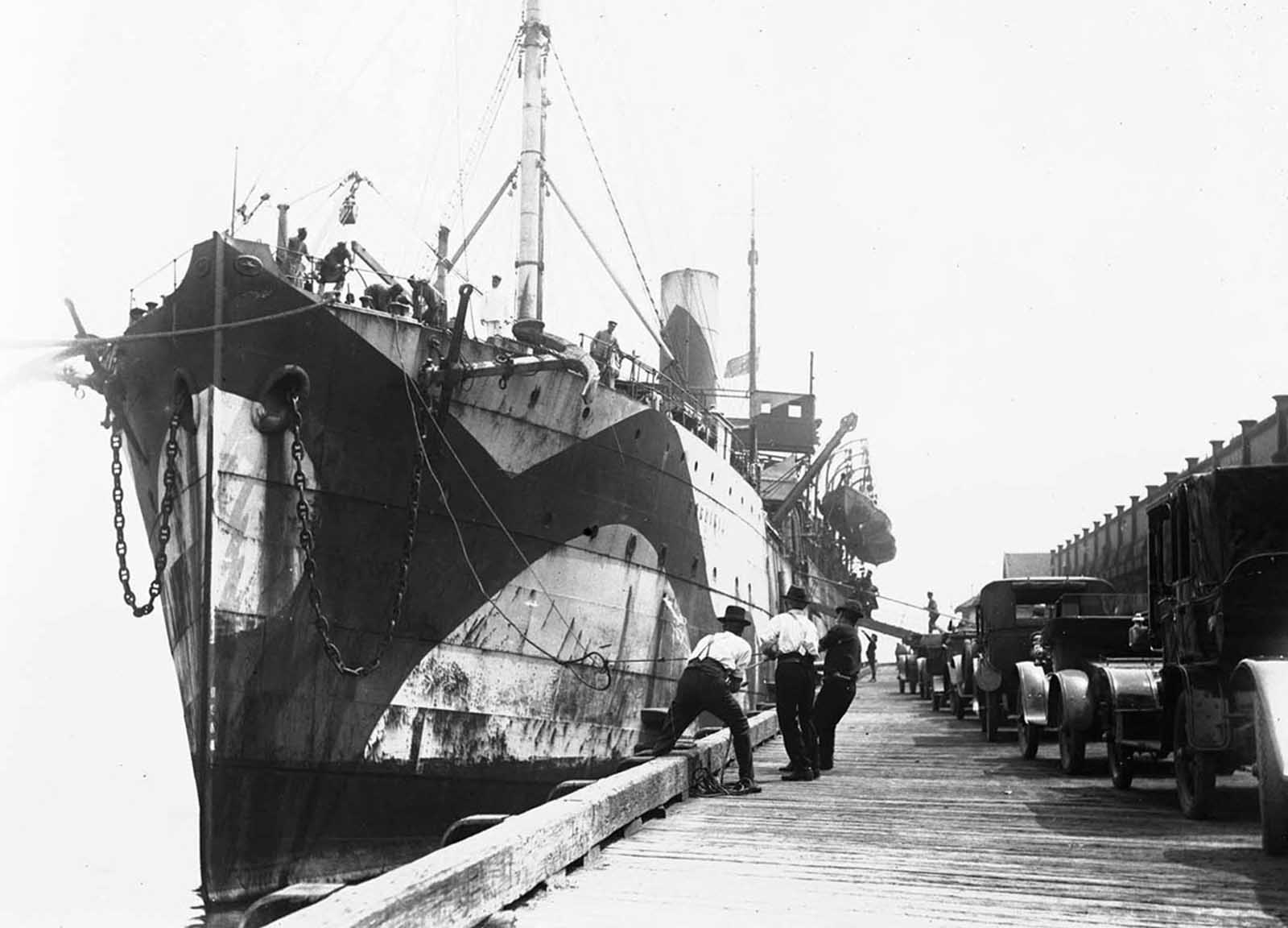 Troop transport Sardinia, in dazzle camouflage, at a wharf during World War I.