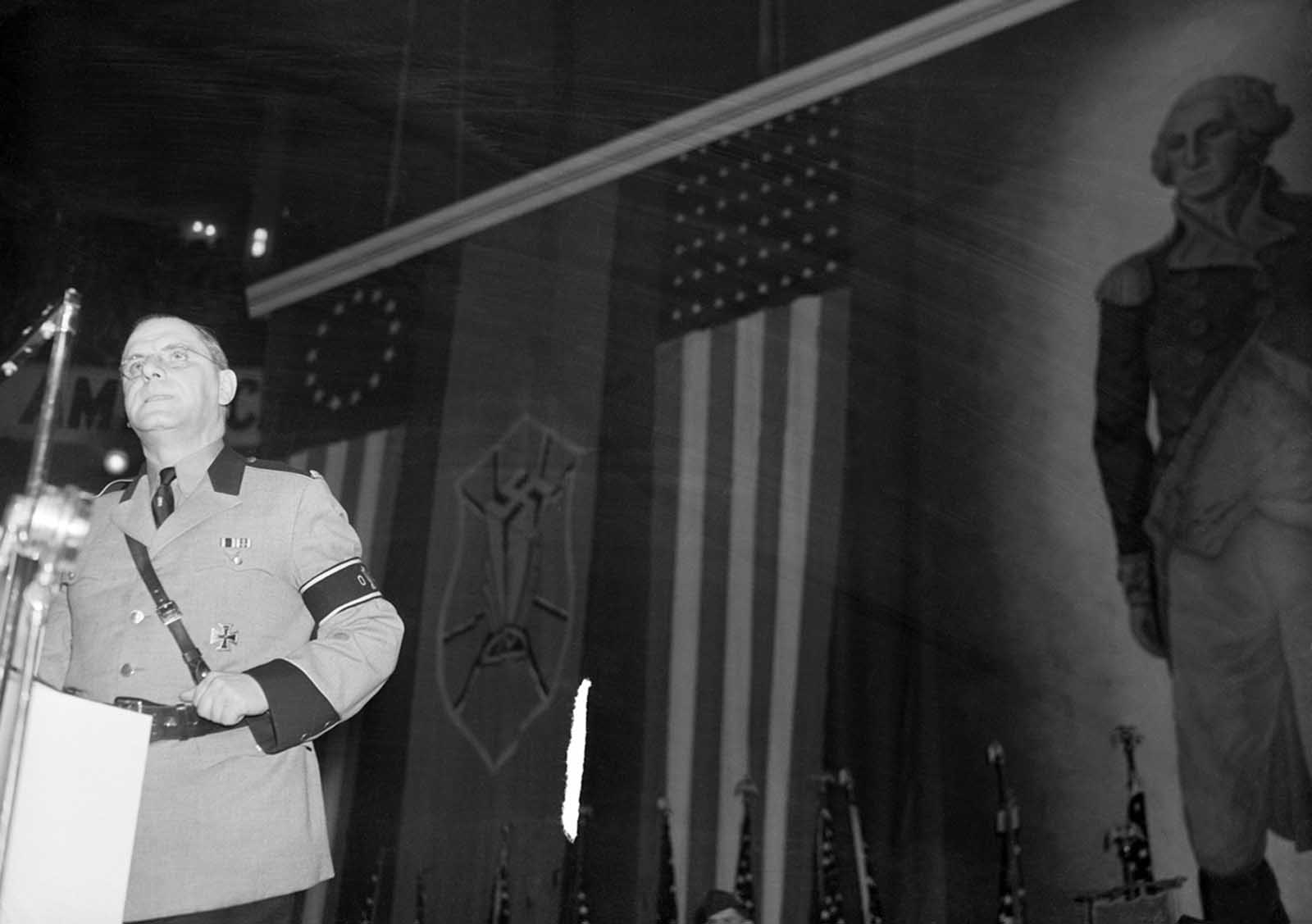 February 20, 1939. Original Caption: The local Fuehrer holds forth. Hewing to the verbal line and letting the syllables fall where they may, Fritz Kuhn, local Fuehrer, leader of the German American Bund, addresses the Bund's heavily guarded