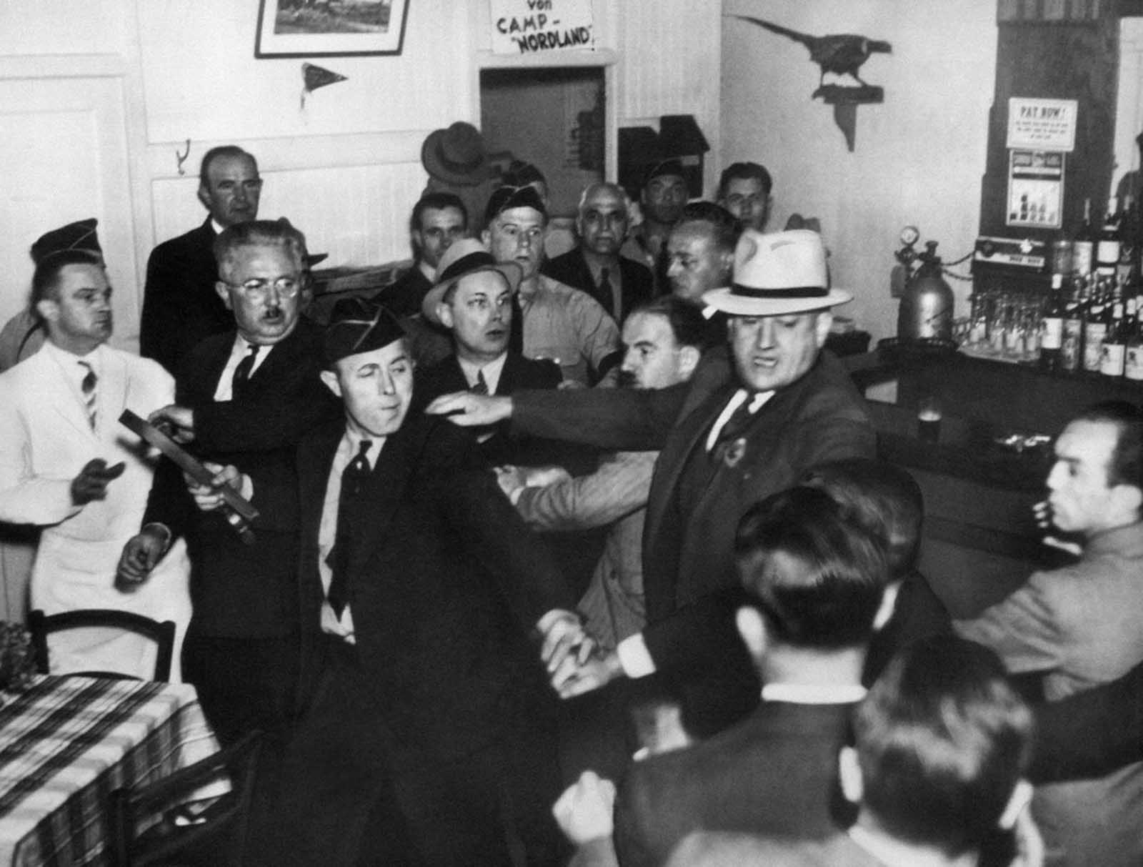 An anti-Nazi crowd rushed the bar entrance of the German-American Bund Hall in Union City, New Jersey, on October 2, 1938 where Fritz Kuhn, bunds-fuehrer, was to make a “victory” speech celebrating Hitler’s occupation of Czechoslovakia. Bund members, including one with a belt as weapon drove the protesters out, but the meeting was disrupted.