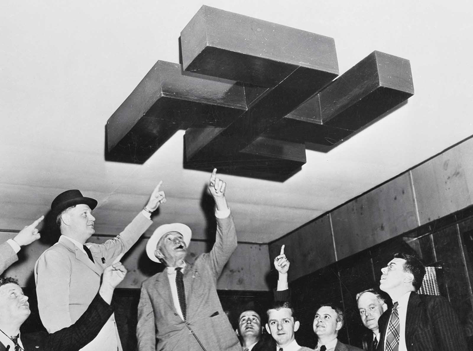 Original caption: Andover, New Jersey: Bund Camp Raided. Sheriffs Deputies who assisted Sheriff Denton J. Quick, of Sussex County in raid on German American Bund Camp Nordland at Andover, New Jersey, shown examining swastika decoration on ceiling of one of the assembly halls at the camp.