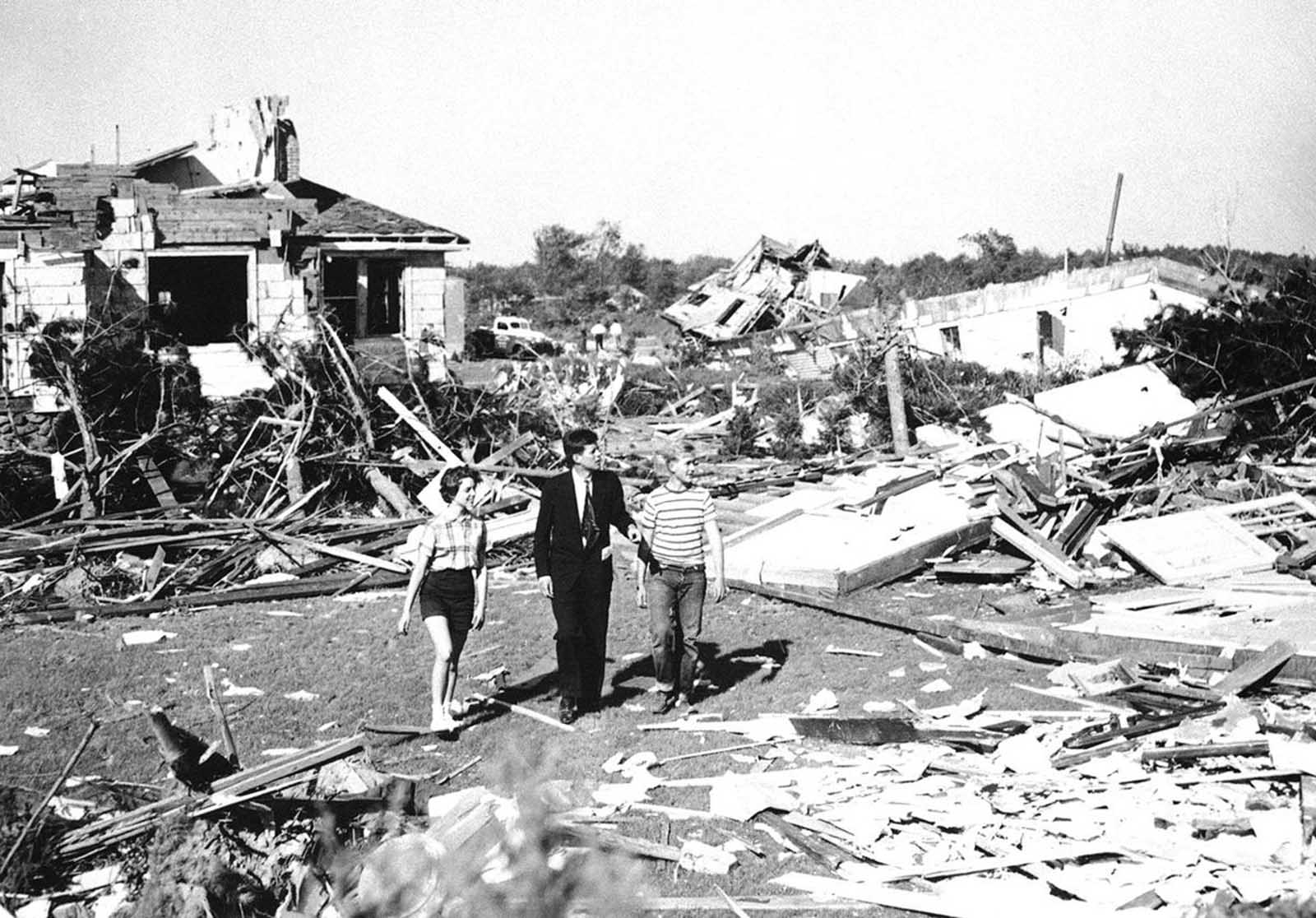 Elected to the U.S. Senate in 1952, here, Senator John F. Kennedy, accompanied by Dick Mayer, 15, and Melissa Tyler, 14, of Shrewsbury, Massachusetts inspects tornado damage in Shrewsbury, on June 10, 1953. At least 86 were left dead in the area by the tornado, 800 injured and 2,500 made homeless.