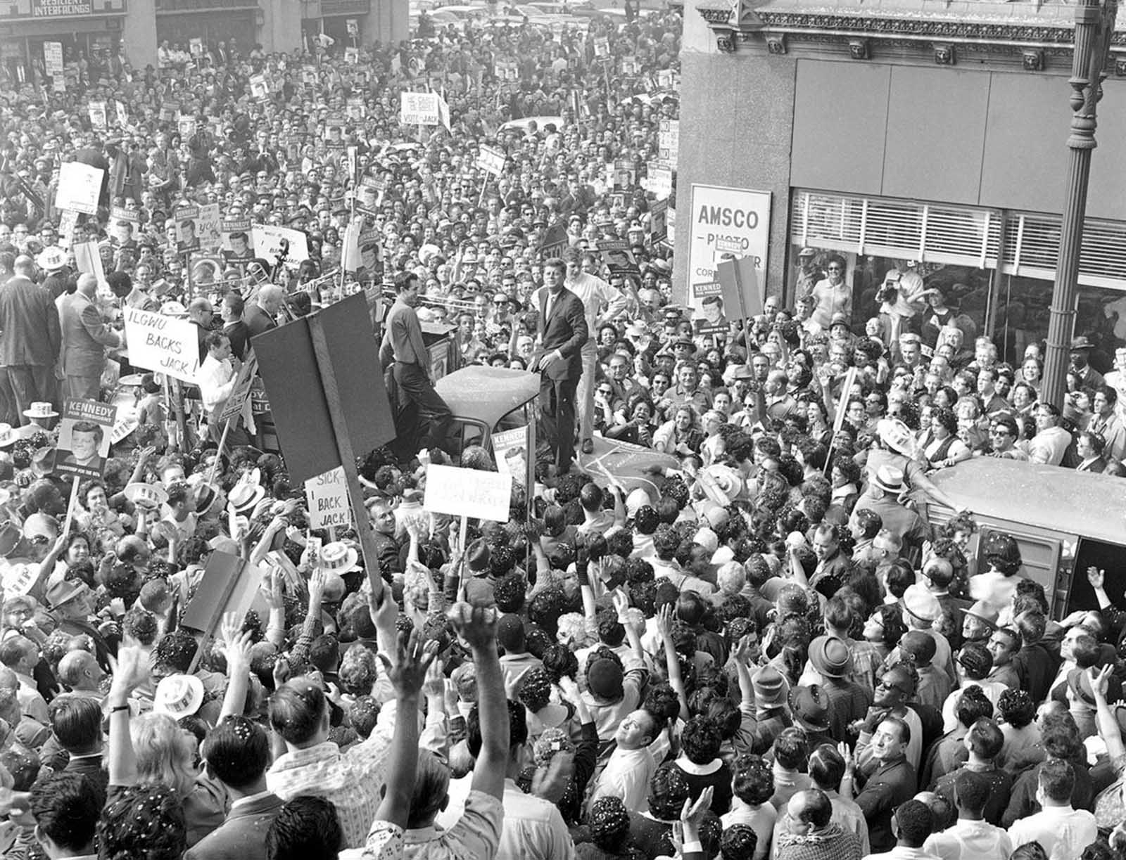 Sen. John F. Kennedy stands on the hood of a truck to acknowledge the cheers of thousands who greeted him in a garment workers rally in downtown Los Angeles, on November 1, 1960.