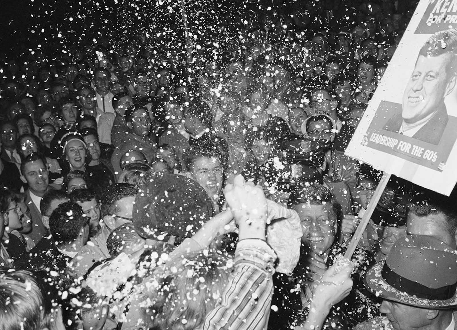 Senator John F. Kennedy, (lower right), grins happily as backers cheer the Democratic presidential candidate in Minneapolis, on October 1st. Kennedy was leaving his hotel for a rally and was surrounded by a large crowd of partisans on October 2, 1960. They waved banner threw confetti and yelled heartily. Between 18,000 and 20,000 attended the rally and thousands more were turned away.