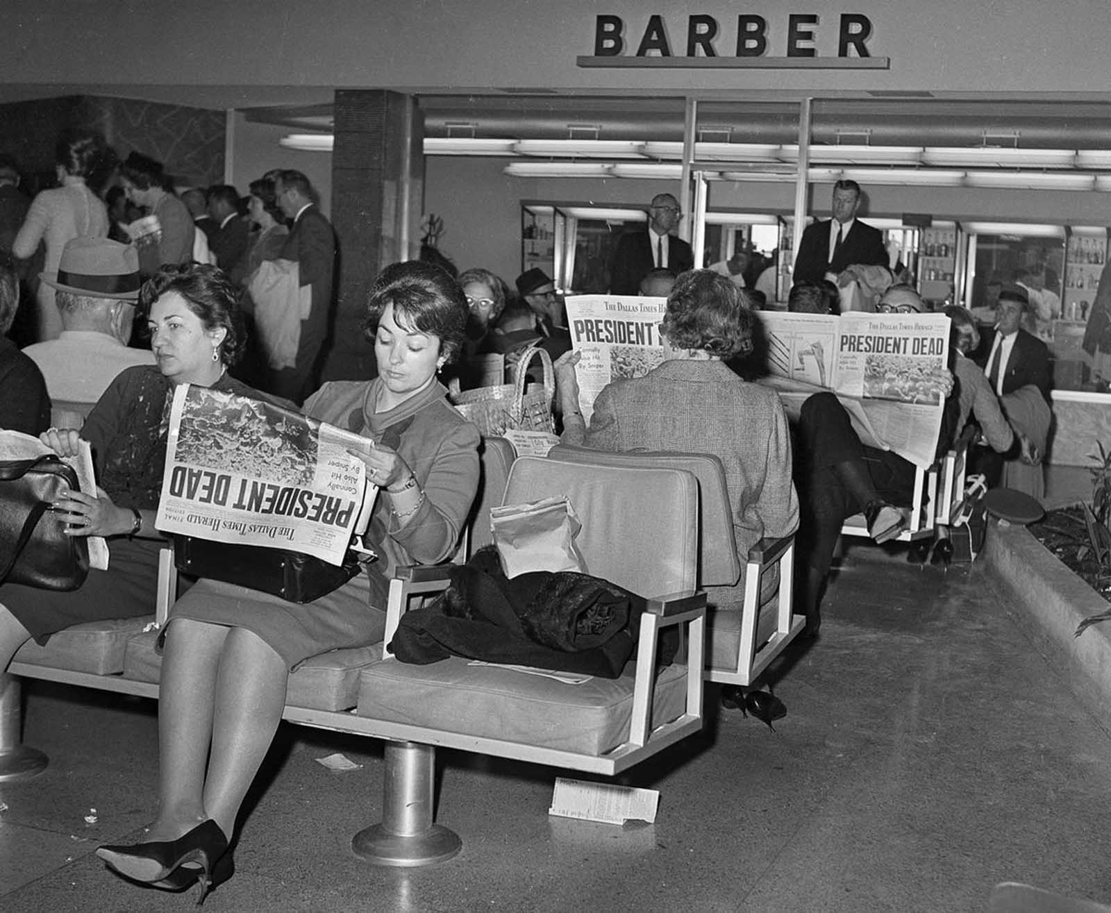 People waiting for flights from Dallas at Love Field read the news of President John F. Kennedy's assassination in the Dallas Times Herald newspaper, on November 23, 1963.