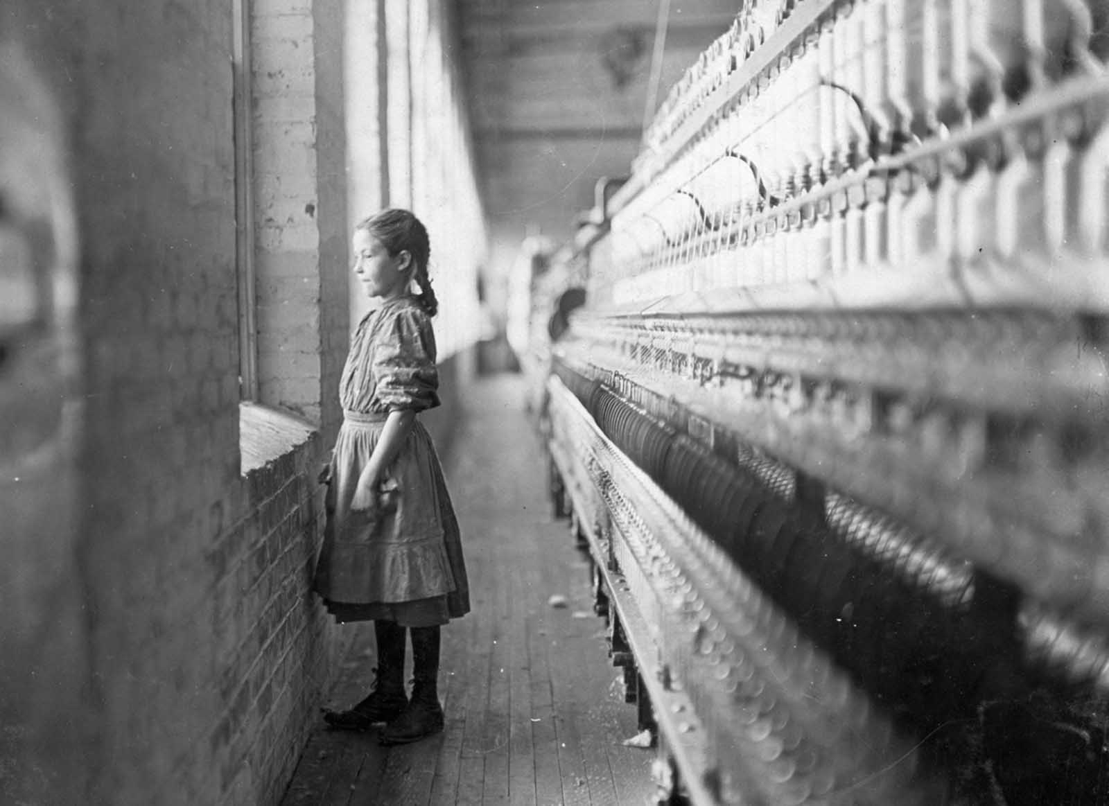 A 10-year-old spinner at the Rhodes Mfg. Co. takes a momentary glimpse of the outside world. She said she had been working there for more than a year. Photographed in Lincolnton, North Carolina, in November of 1908.