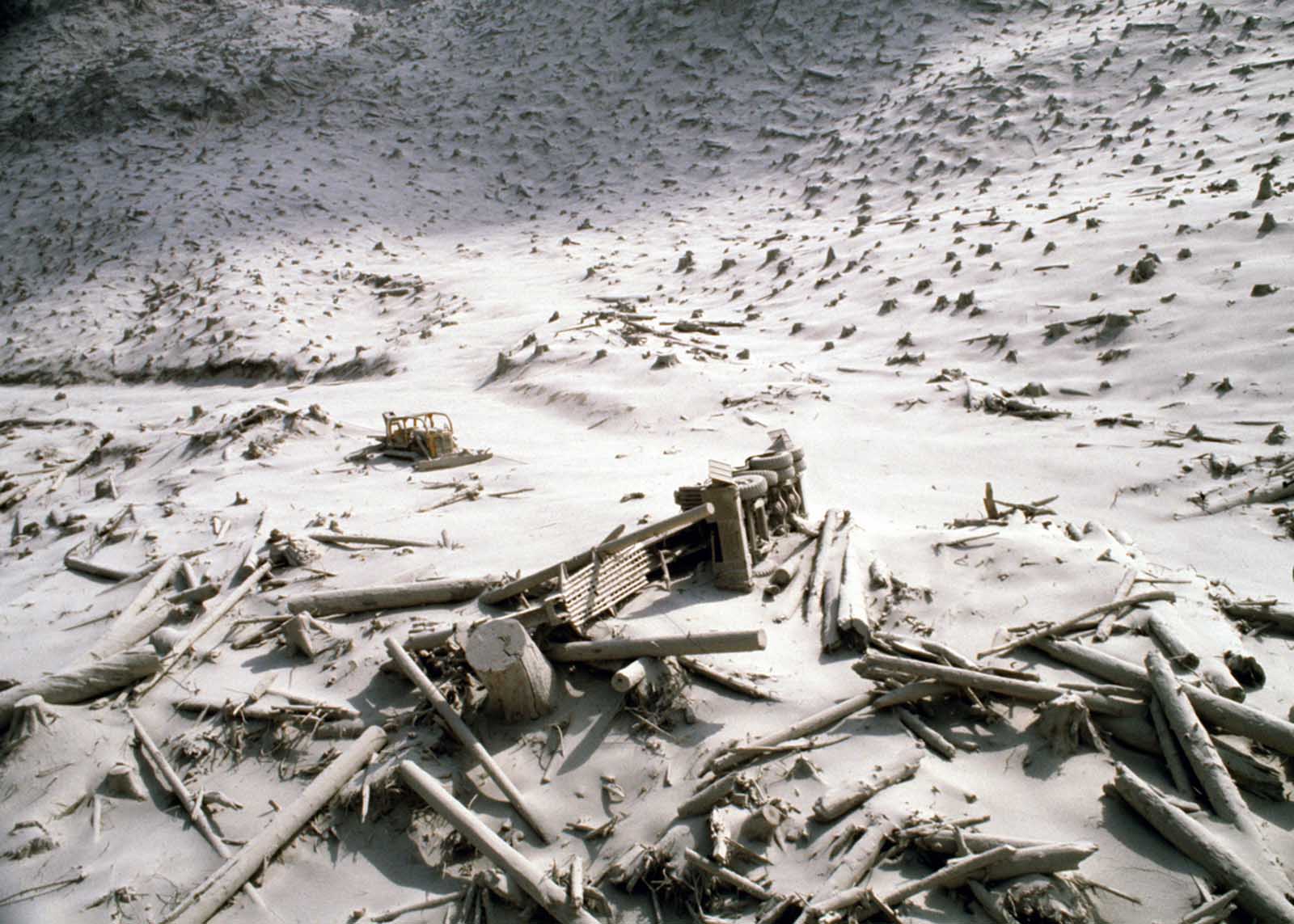 A wrecked logging truck and crawler tractor are shown amidst ash and downed trees near Mount St. Helens two days after an explosive eruption.