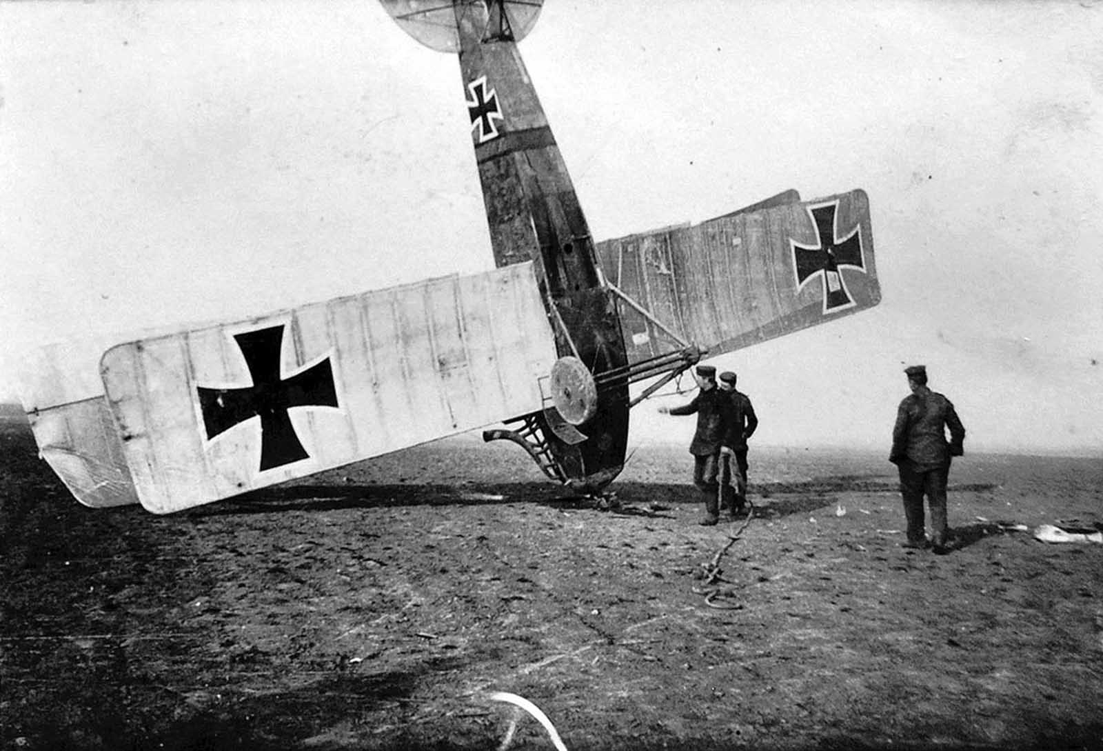 German soldiers attend to an upended German aircraft.