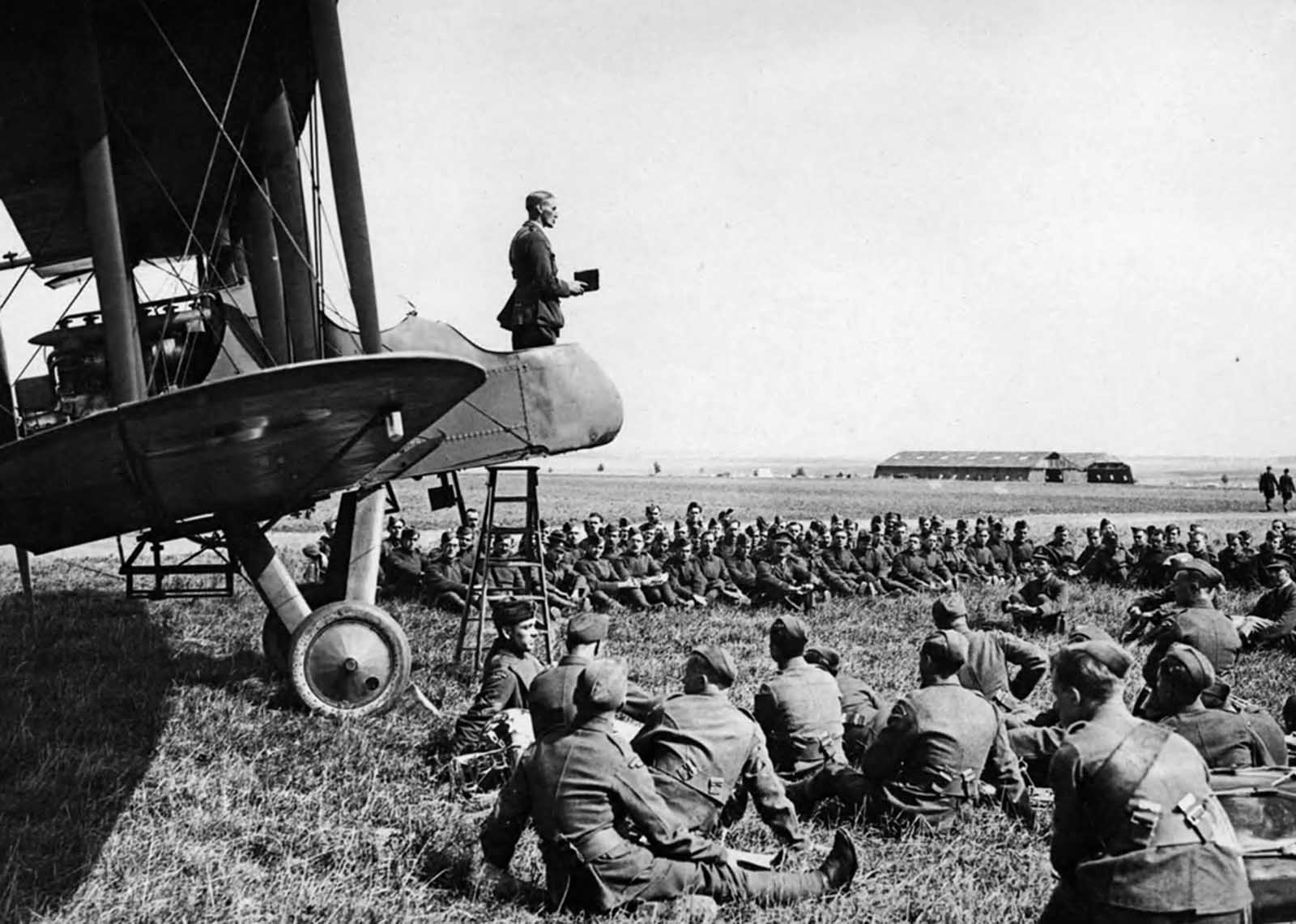 A Sunday morning service in an aerodrome in France. The Chaplain conducting the service from an aeroplane.