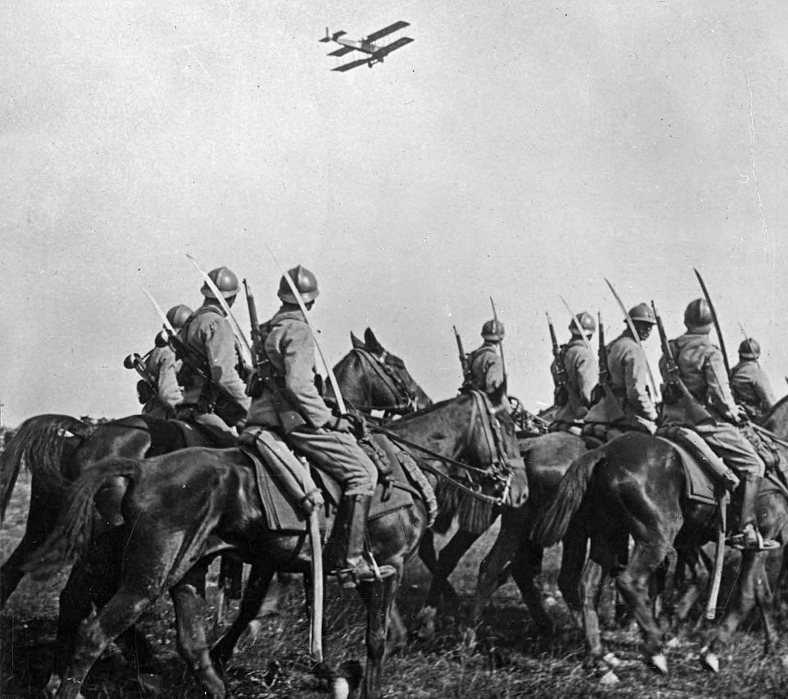 French Cavalry observe an Army airplane fly past.