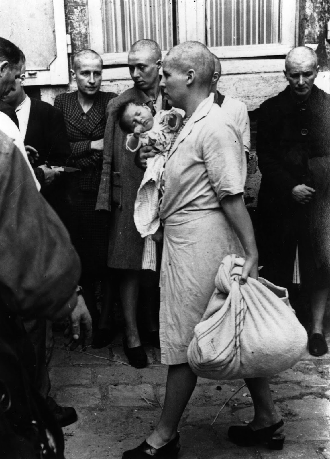 A woman collaborator and her baby, whose father is German, returns to her home after having her head shaven following the capture of Chartres by the Allies.
