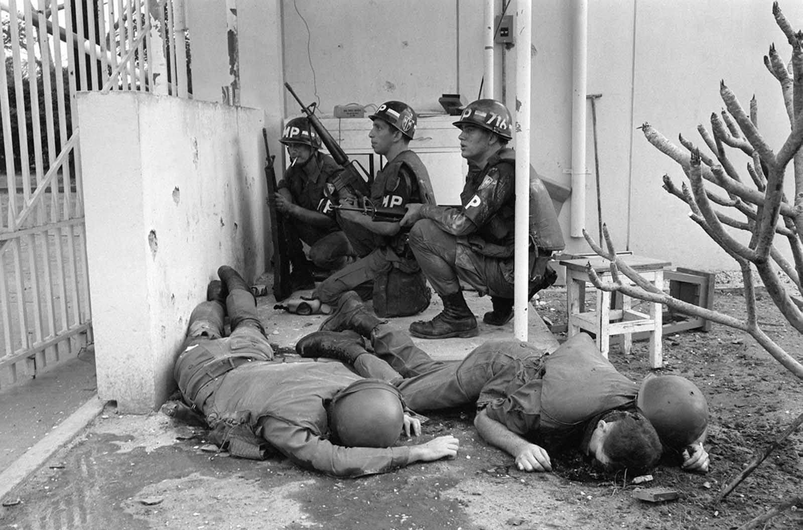 With dead U.S. soldiers in the foreground, U.S. military police take cover behind a wall at the entrance to the U.S. Consulate in Saigon on the first day of the Tet Offensive, January 31, 1968. Viet Cong guerrillas had invaded the grounds of the U.S. embassy compound in the earliest hours of the coordinated Communist offensive.