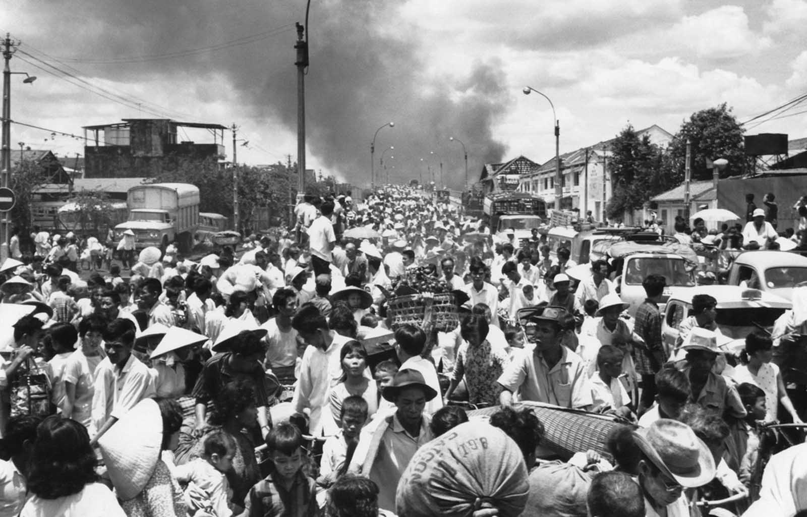 Smoke rises from the southwestern part of Saigon on May 7, 1968, as residents stream across the bridge leaving into the capital to escape heavy fighting between the Viet Cong and South Vietnamese soldiers.