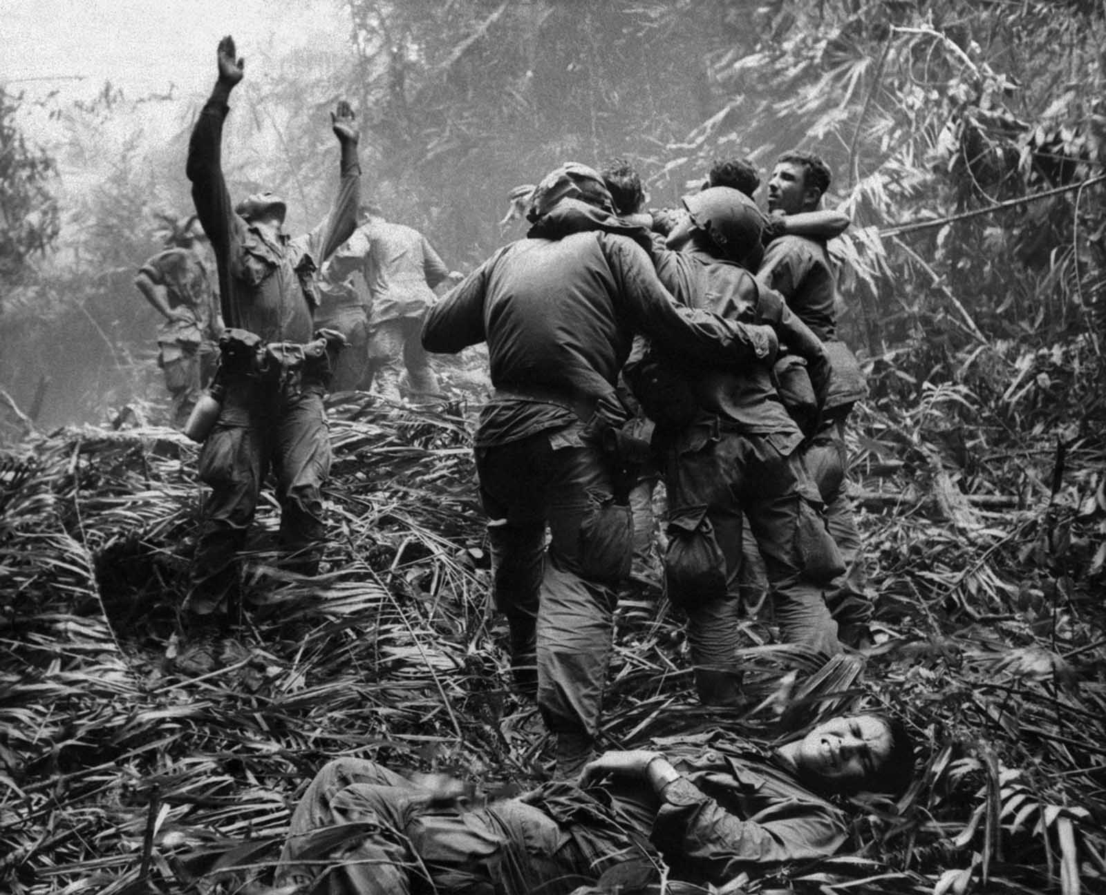 As fellow troopers aid wounded comrades, the first sergeant of A Company, 101st Airborne Division, guides a medevac helicopter through the jungle foliage to pick up casualties suffered during a five-day patrol near Hue, in April of 1968.