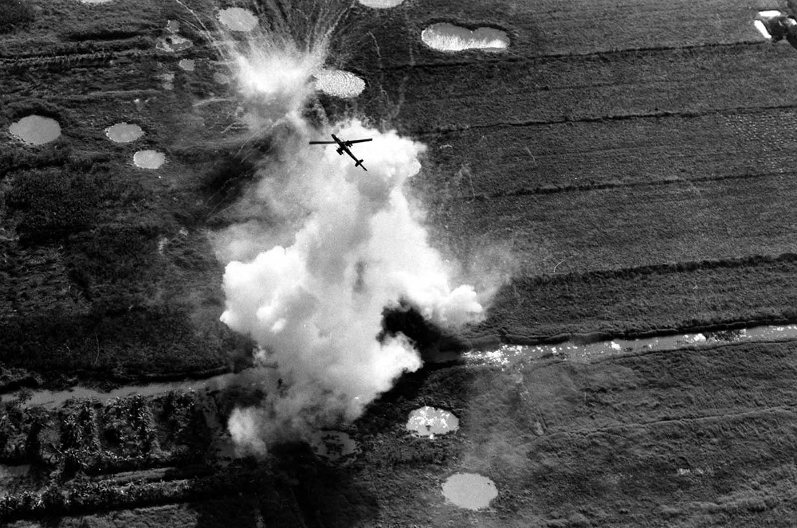 A Cobra helicopter gunship pulls out of a rocket and strafing attack on a Viet Cong position near Cao Lanh in the Mekong Delta on January 22, 1969. Large craters caused by air and artillery strikes brought in on the area can be seen near the white explosion.