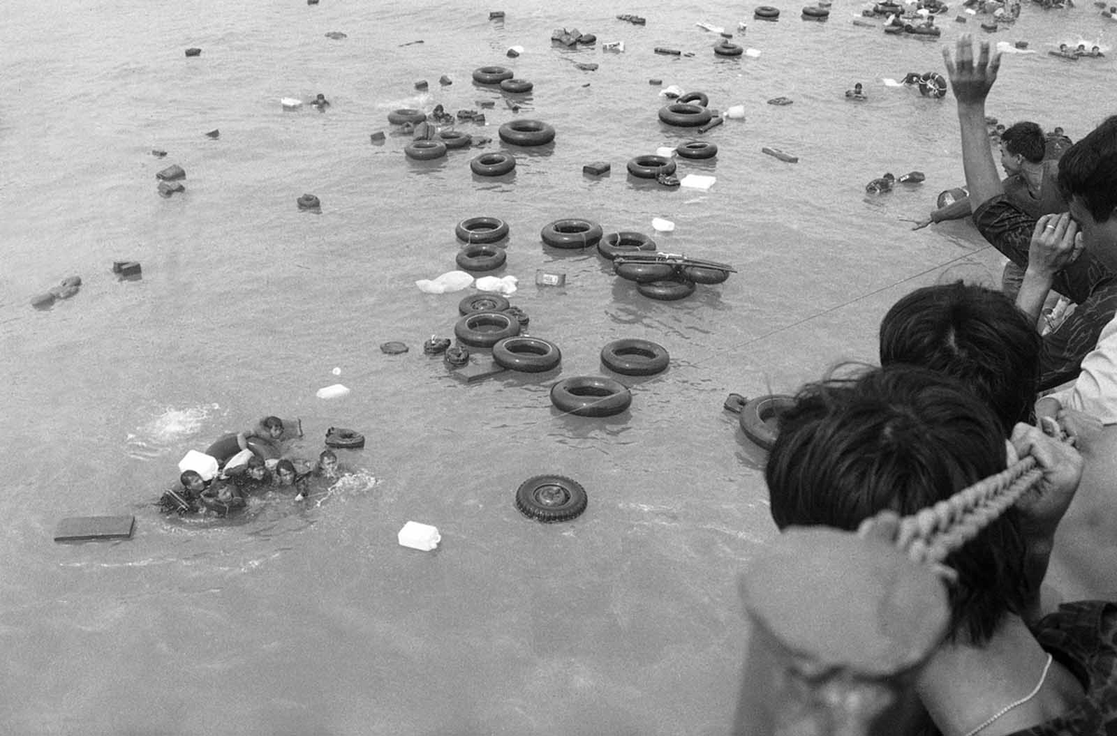A cluster of South Vietnamese marines, some of whom unable to swim, hold onto inner tubes and empty plastic containers as buddies throw them a line to pull them aboard a navy LST off China Beach at Danang as they fled the port city in April of 1975.