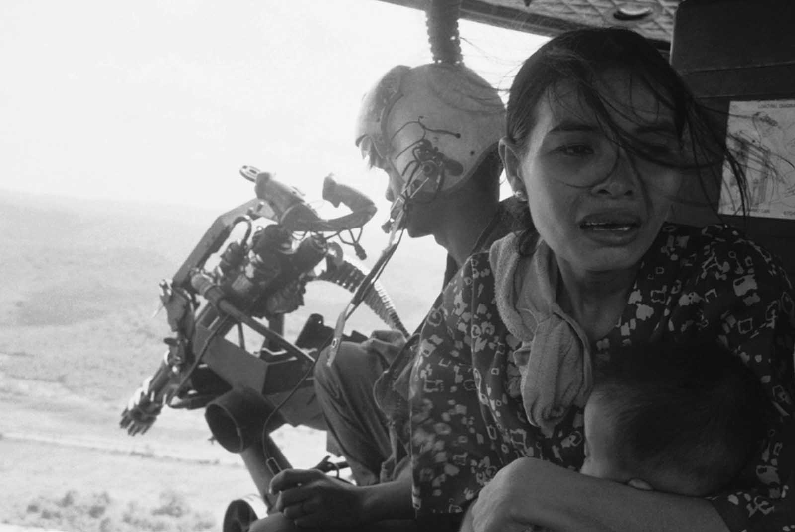 A refugee clutches her baby as a government helicopter gunship carries them away near Tuy Hoa, 235 miles northeast of Saigon on March 22, 1975. They were among thousands fleeing from recent Communist advances. With U.S. forces out of the country, North Vietnamese troops tested South Vietnamese defenses (and the willingness of the U.S. to return to the fight) starting in 1974, and began capturing territory.
