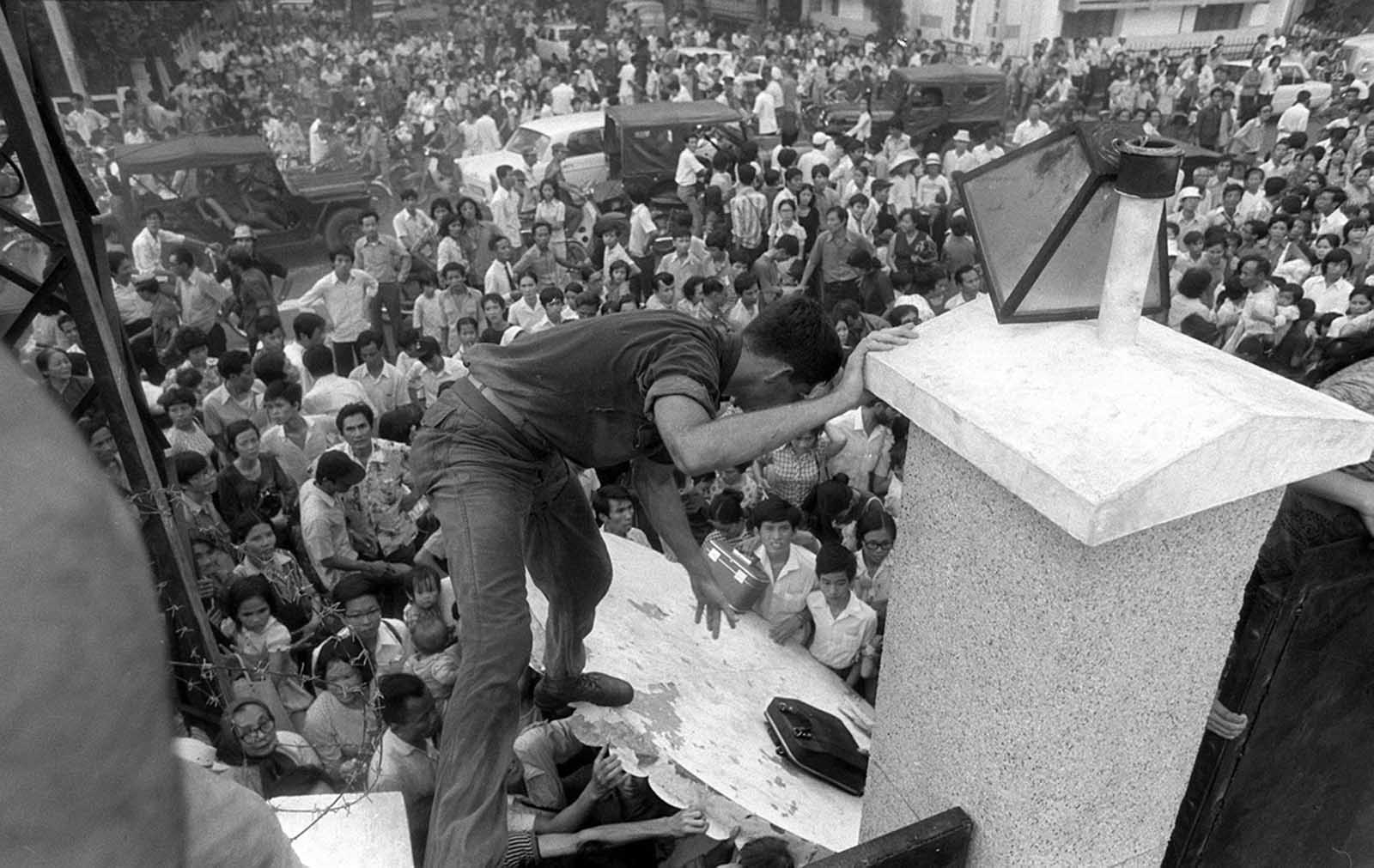 The Fall of Saigon. Fleeing advancing North Vietnamese forces, mobs of South Vietnamese civilians scale the 14-foot wall of the U.S. embassy in Saigon, April 29, 1975, trying to reach evacuation helicopters as the last Americans departed from Vietnam.